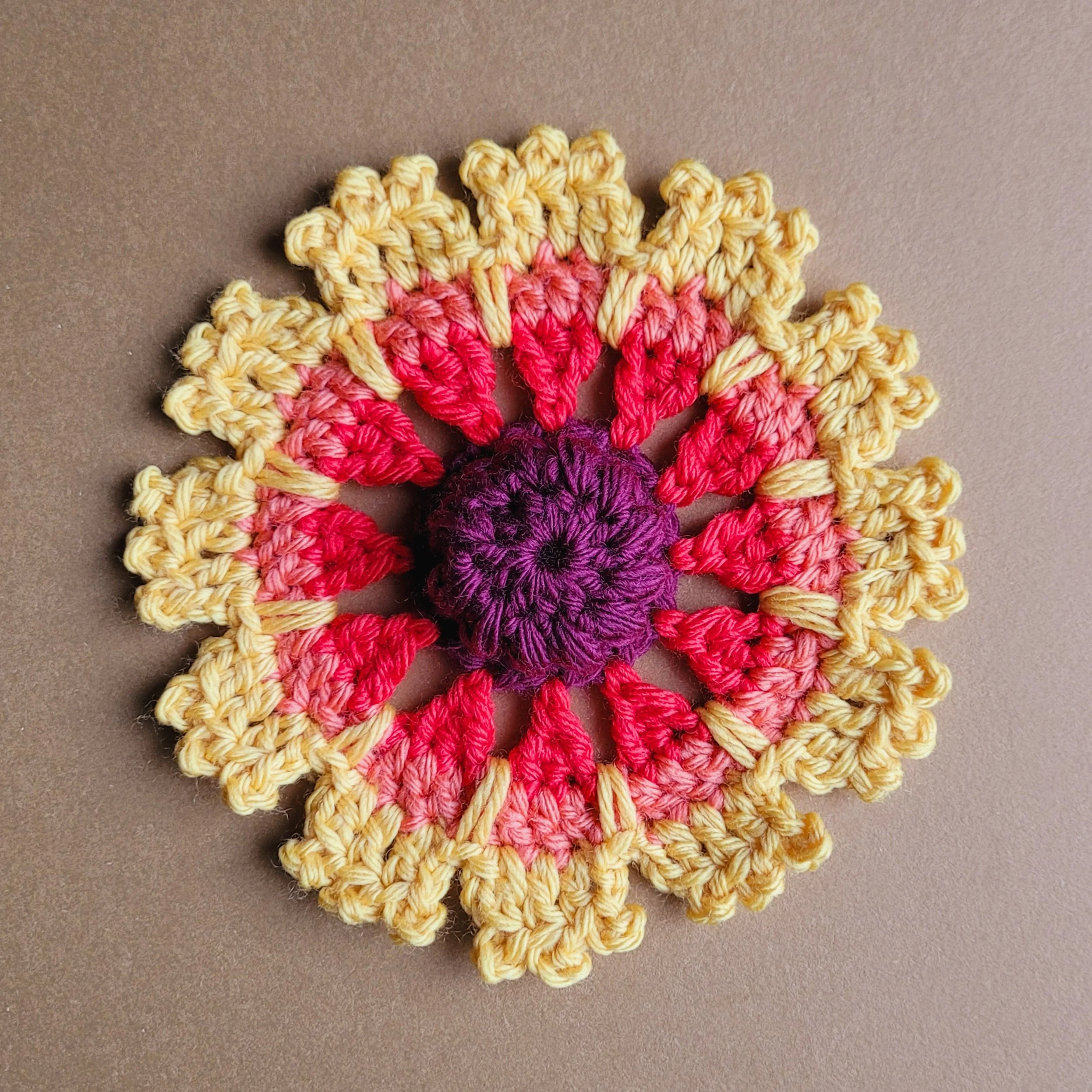 crochet flower in purple, red, and yellow