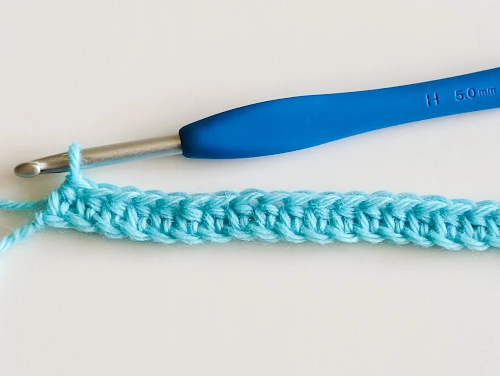 A row of half double crochet worked into the foundation chain. The yarn is light blue.