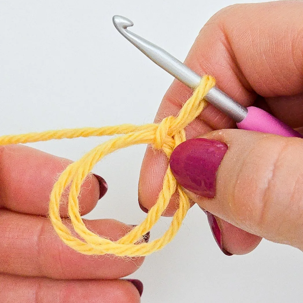 Closeup of an adjustable ring made with yellow yarn.