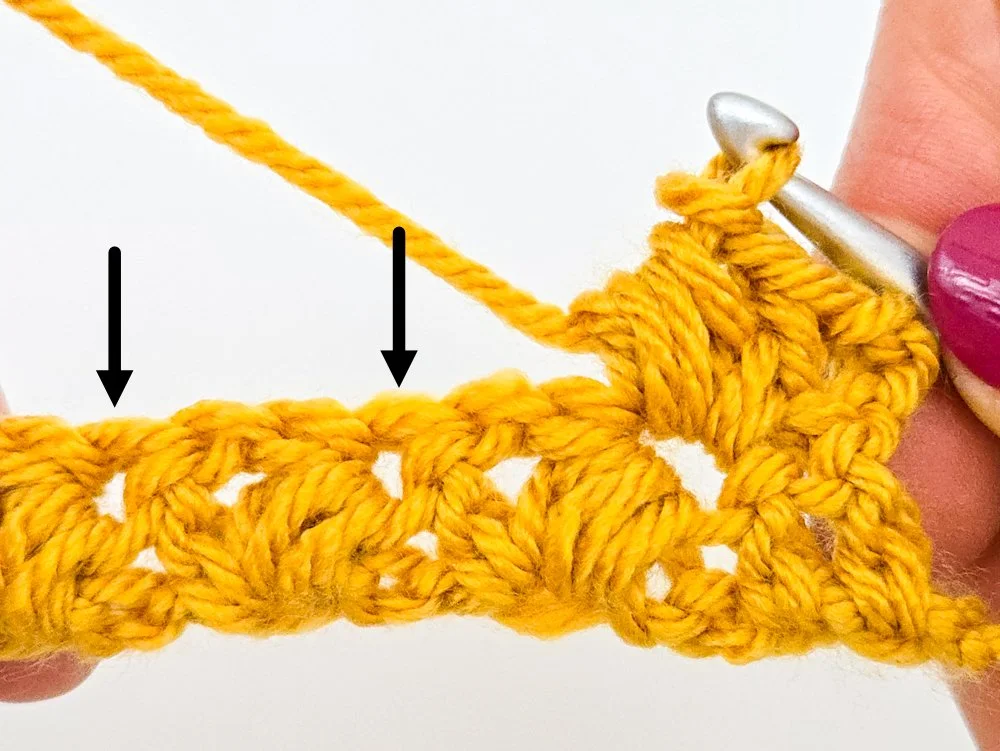 Two black arrows point to the next double crochets in which you will work puff V-stitches.