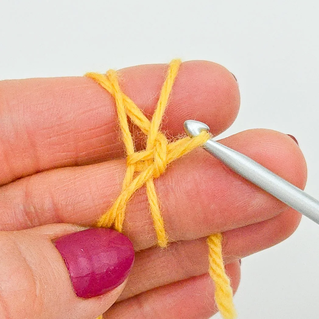 A chain made with yellow yarn. This chain holds the two loops together.