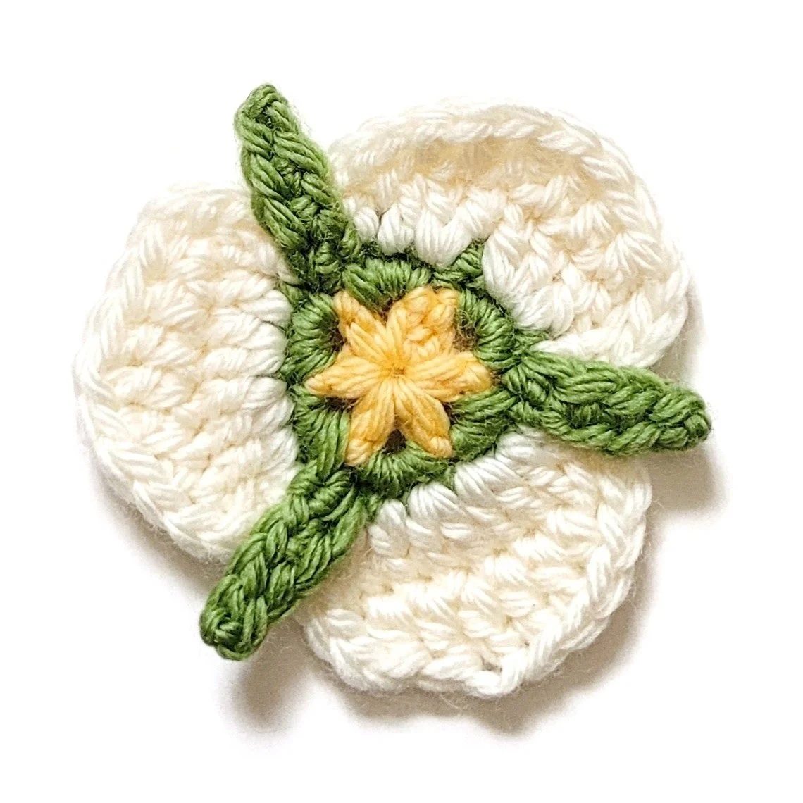 A crochet mariposa lily made with white, green, and yellow yarn.
