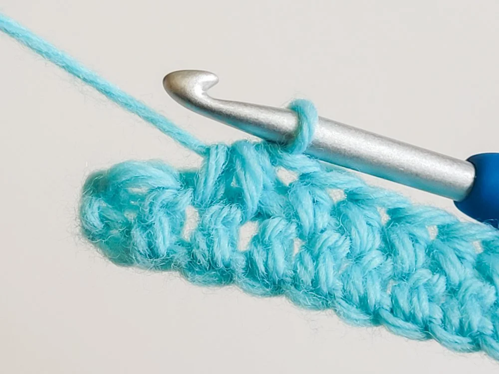 Decrease worked into the next two spaces between stitches.