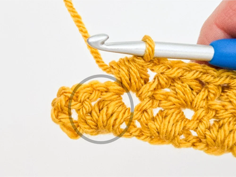 The last puff V-stitch of the row is circled in gray.