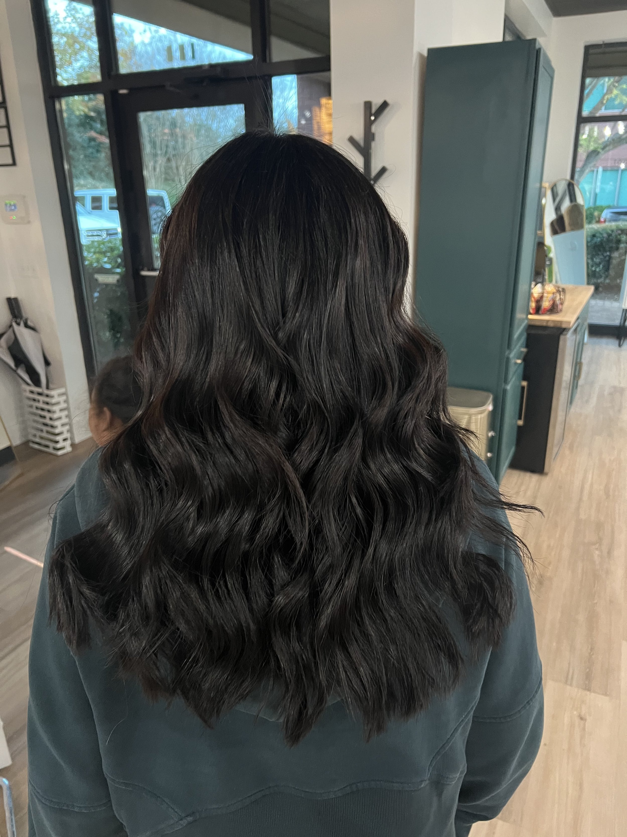 Woman with long wavy dark hair inside a modern room.