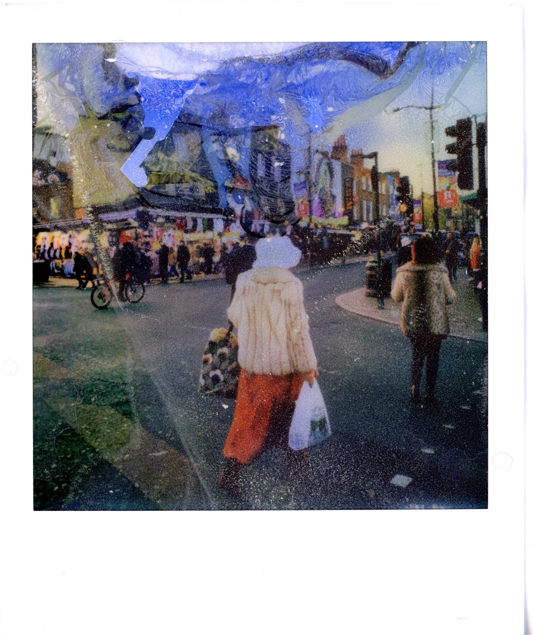 A Polaroid of a woman walking in the street with a shopping bag. The Polaroid is blurry with watercolors.
