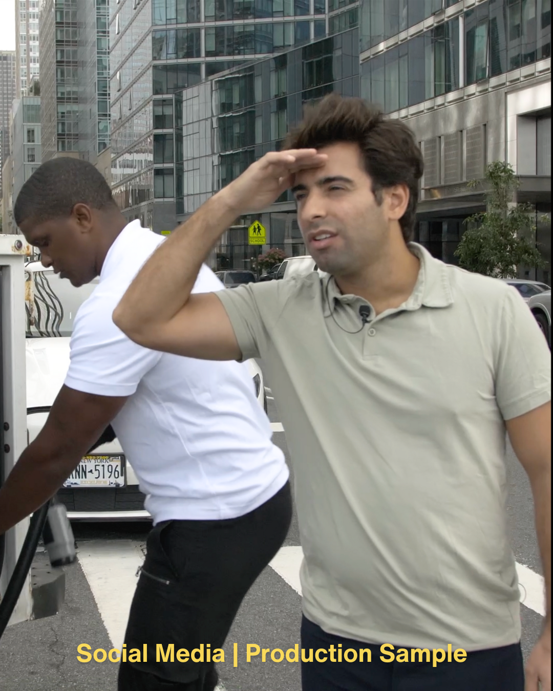 Two men standing on a city street, one looking into a service meter box and the other shielding his eyes from the sun.