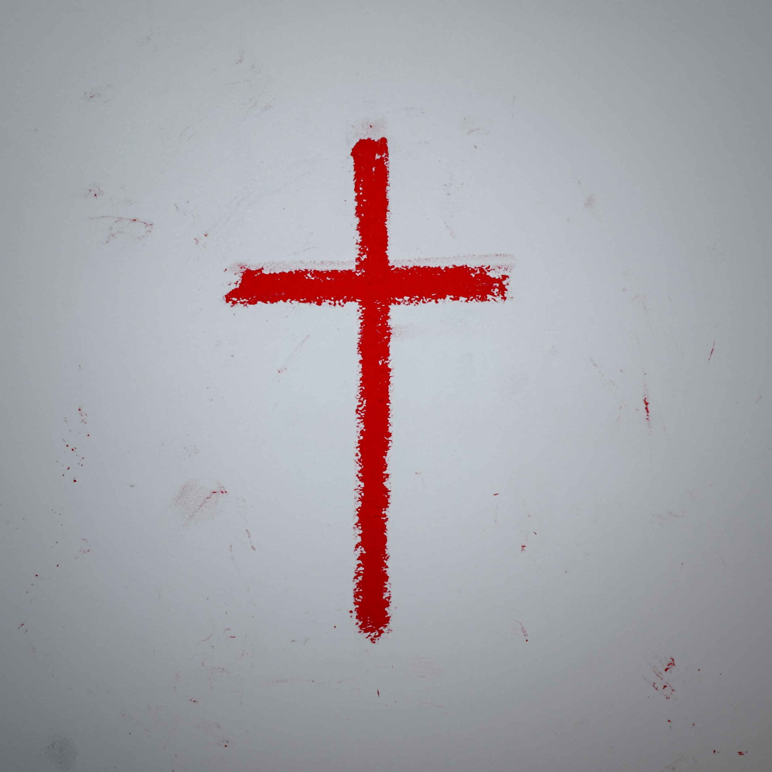 Red paint applied in the shape of a downward pointing arrow on a white surface.
