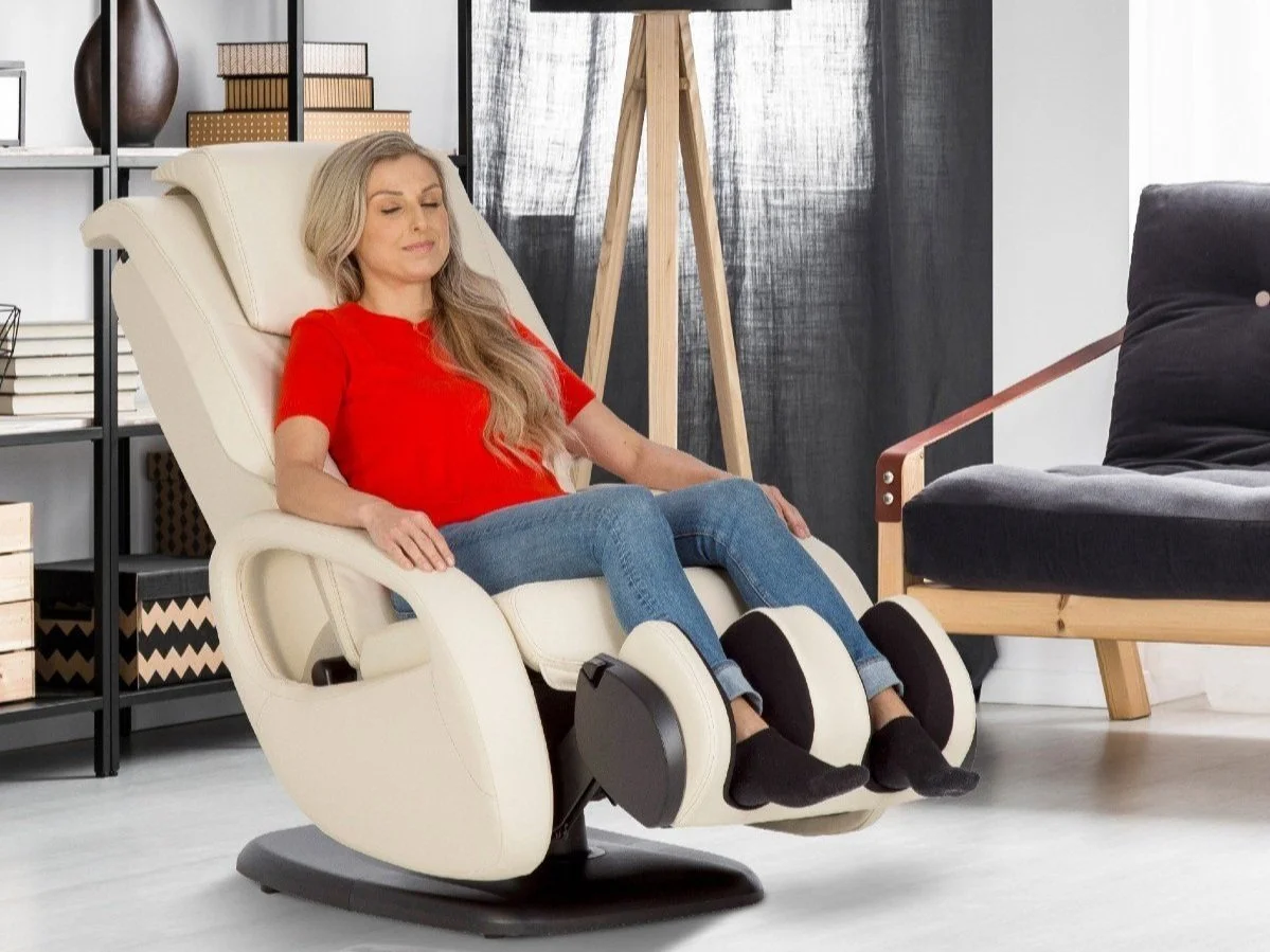 A woman sitting comfortably in a medical massage chair in a modern living room, with her eyes closed and a relaxed expression.