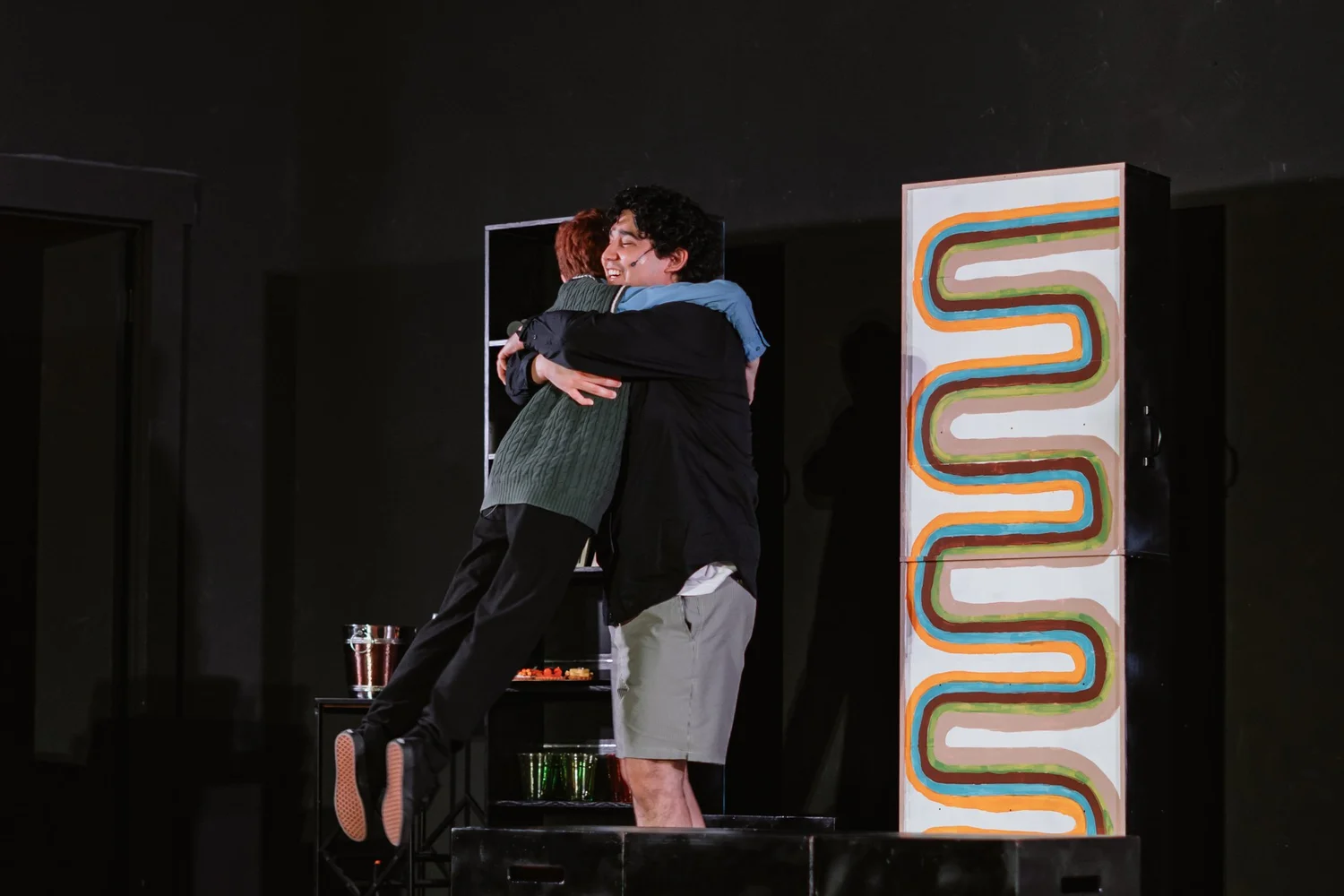 Two actors embrace onstage in Merrily We Roll Along