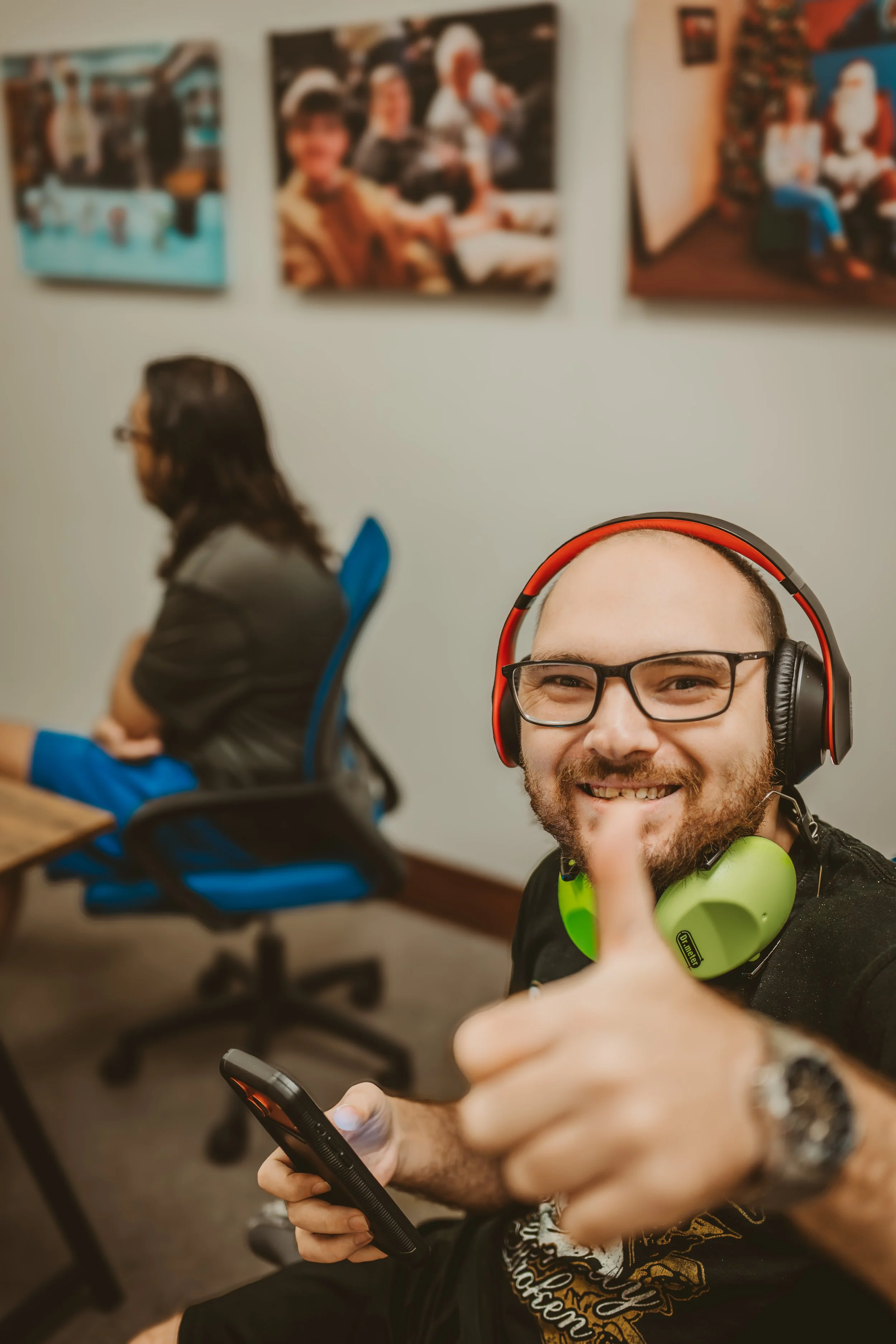 A man with his headphones on gives a thumbs up to the camera