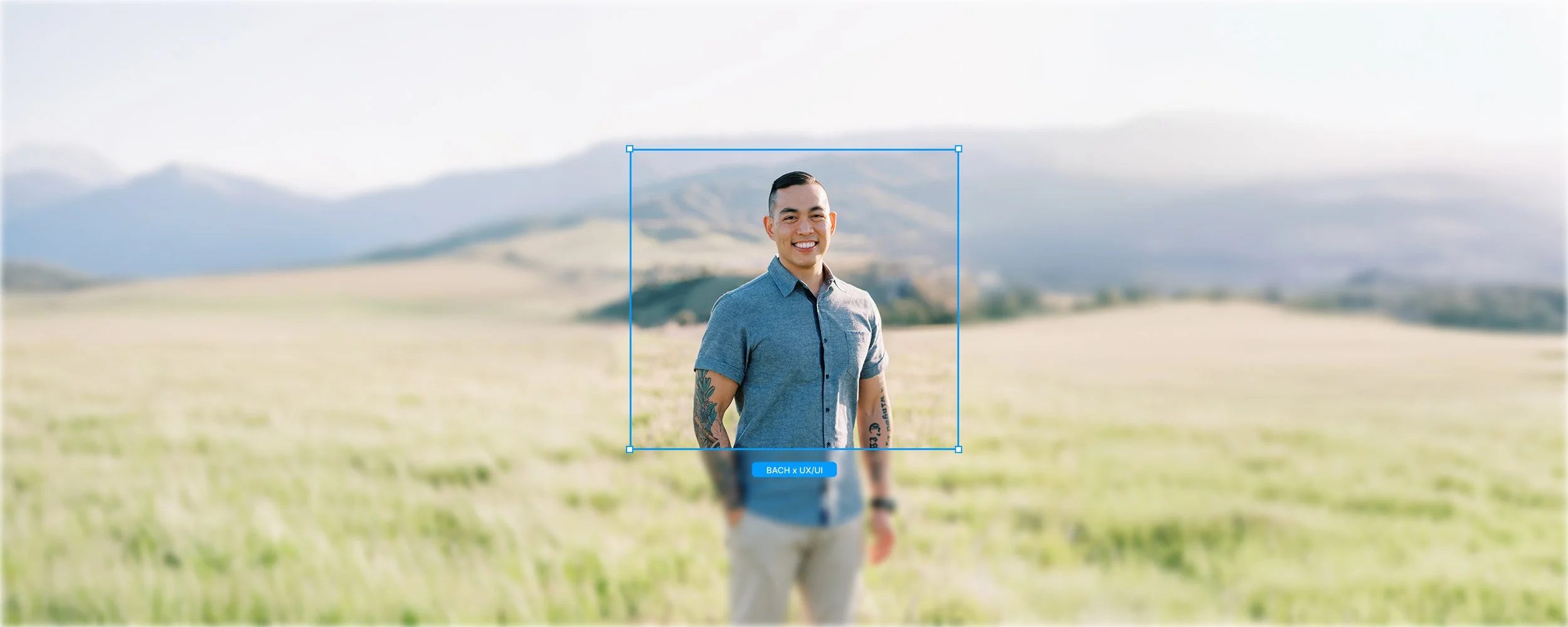 Bach Nguyen smiling in a sunlit grassy field with hills behind him