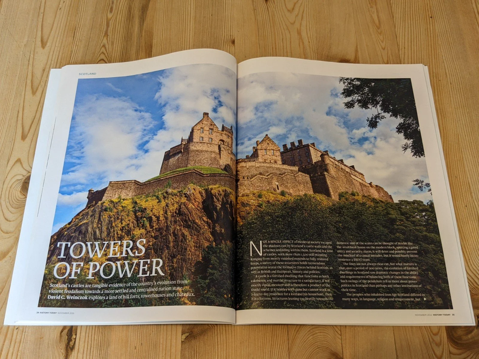 Open spread of Historu Today magazine on a wooden table. The title reads, 'Towets of Power', with an image of Edinburgh Castle and the castle crag in the late evening sun.