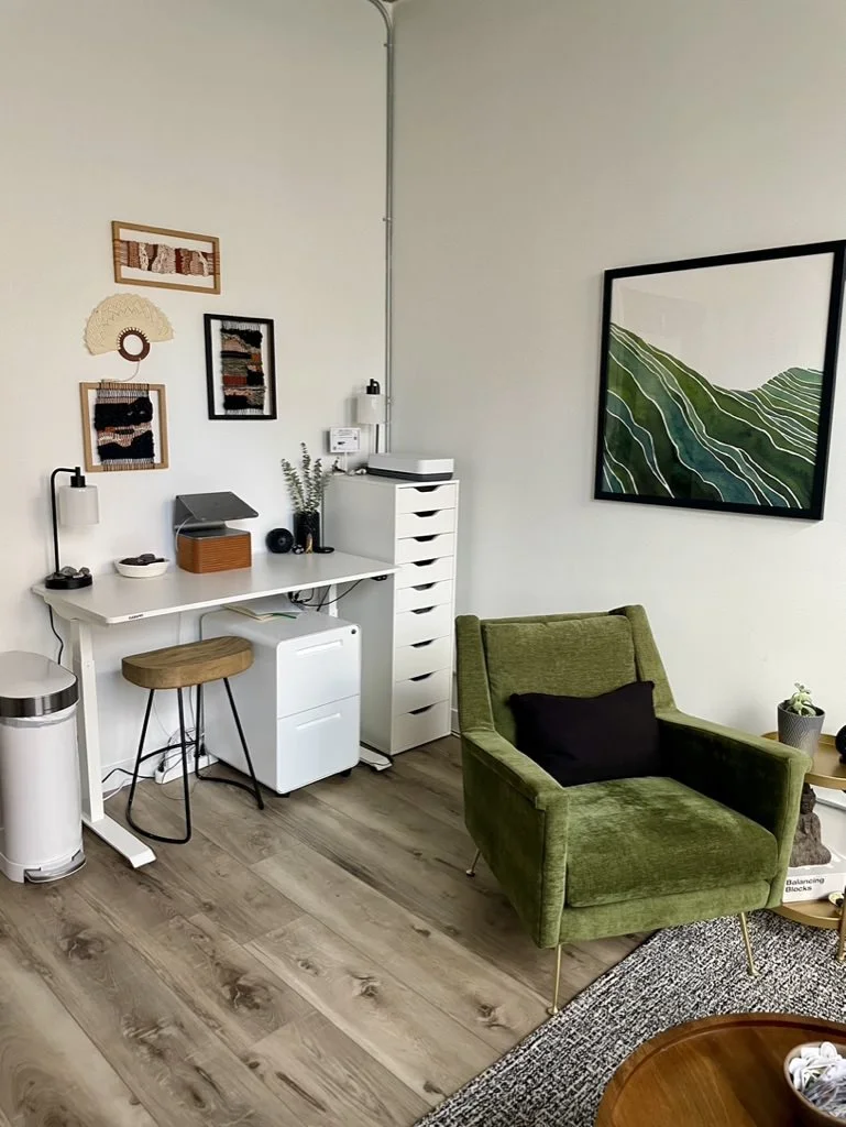 InnerBloom Therapy Practice modern office interior with velvet green chair, stand up desk, wall art, white drawers, and wood floors in Chicago, IL