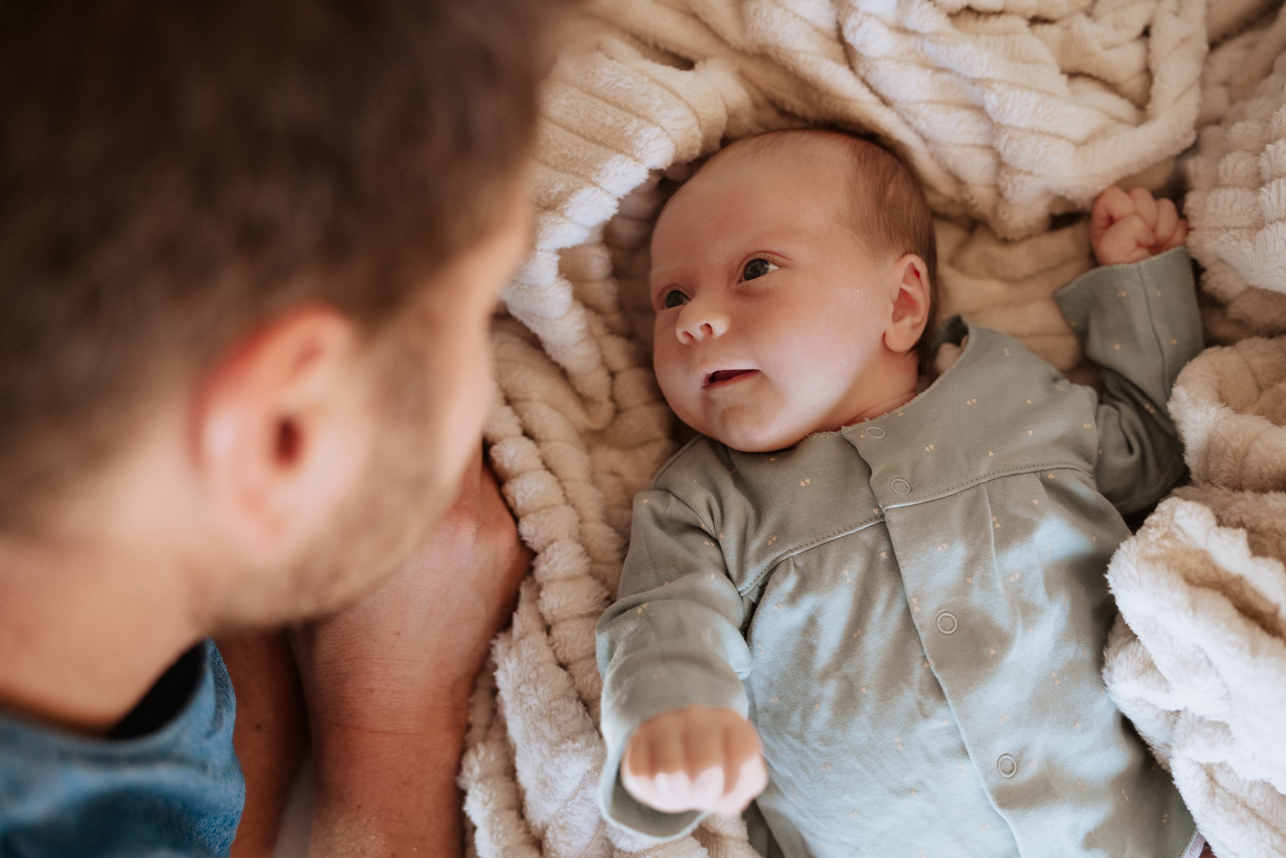 Baby freut sich über Papa während Newbornshooting