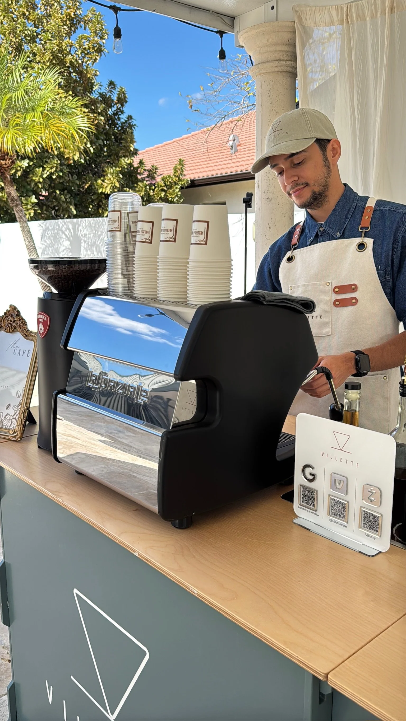 A barista preparing coffee at an outdoor wedding event catered by Villette