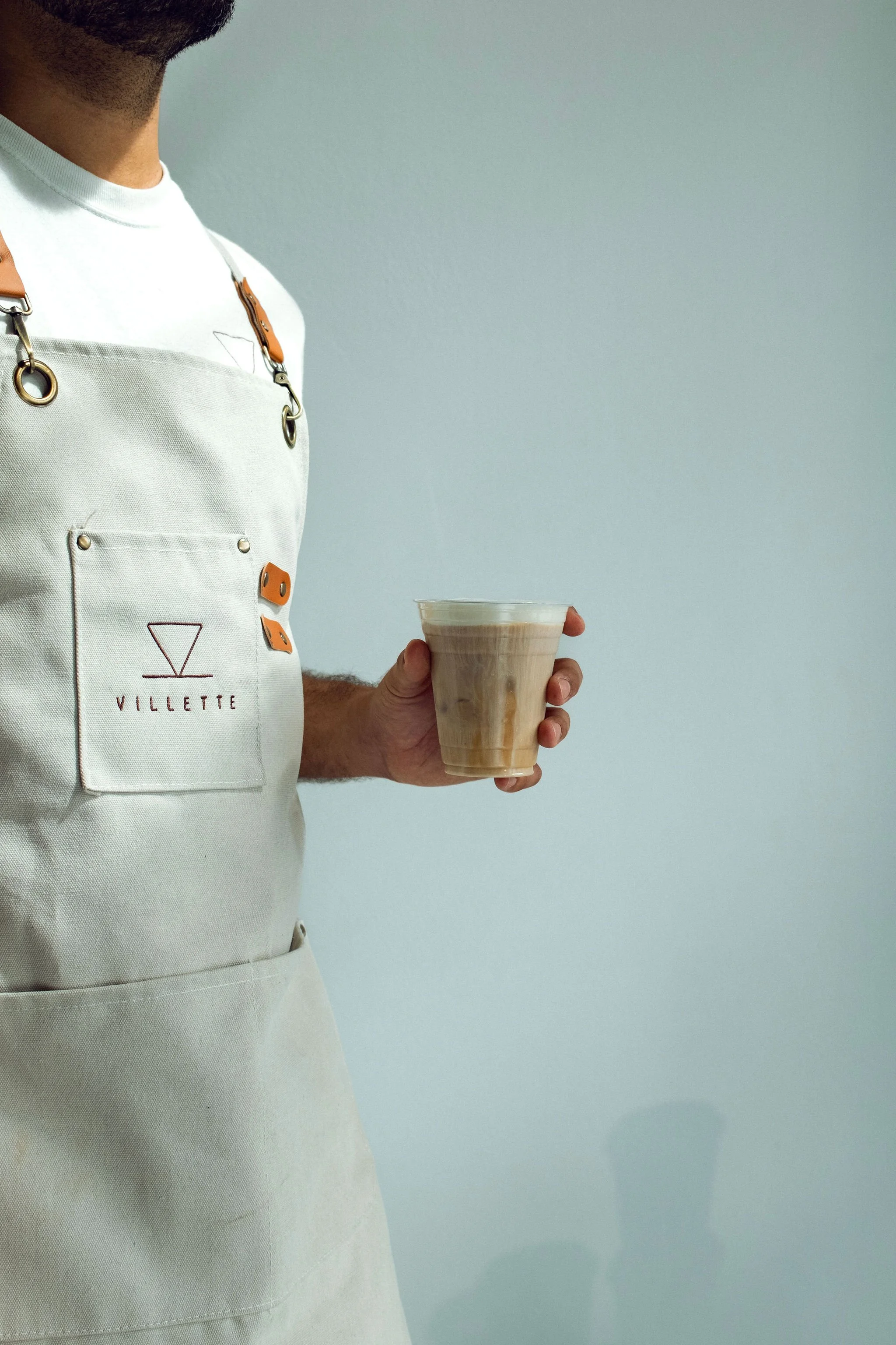 Barista holding iced latte served by Villette Coffee Cart at a Miami event