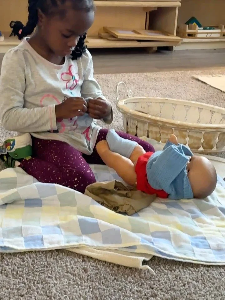 💗 In our Montessori classrooms, Practical Life work helps children build independence, confidence, and empathy.

This young student is carefully dressing a baby doll &mdash; a beautiful example of care for others in action. Through these lessons, ch