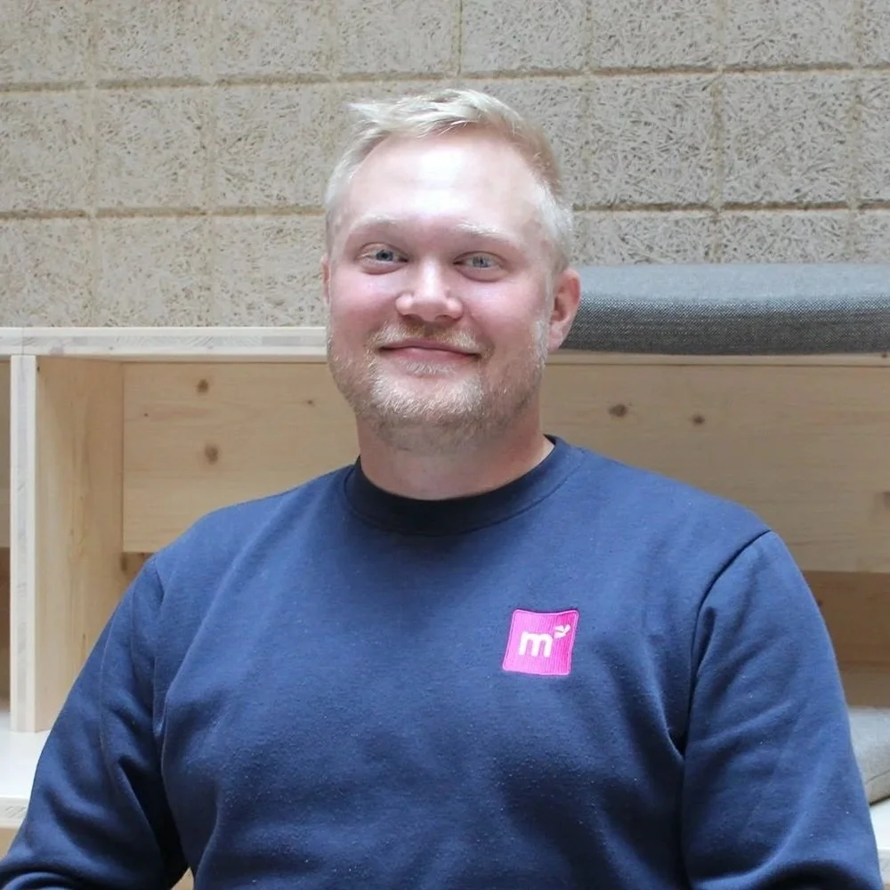 blonde-haired man facing the camera with a faint smile.