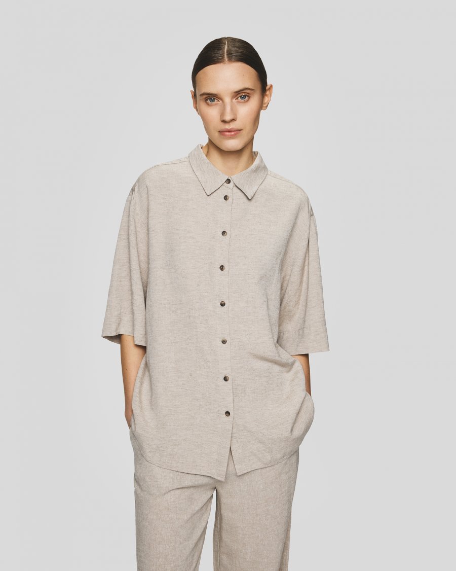 Vrouw draagt een loose fit MSCHViana Ginia shirt van Moss Copenhagen in kleur sand melange.
