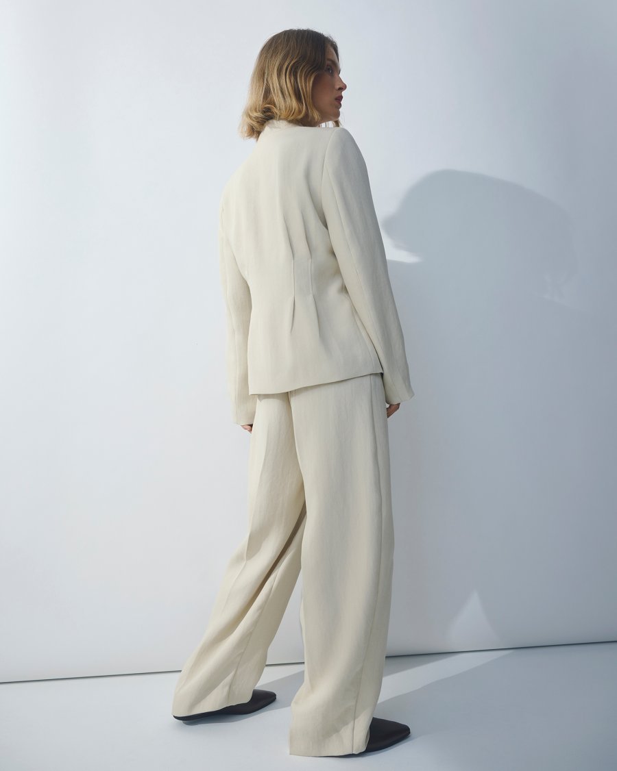 Achterzijde van vrouw met MSCHEsteriane blazer en broek in oatmeal melanger van Moss Copenhagen.