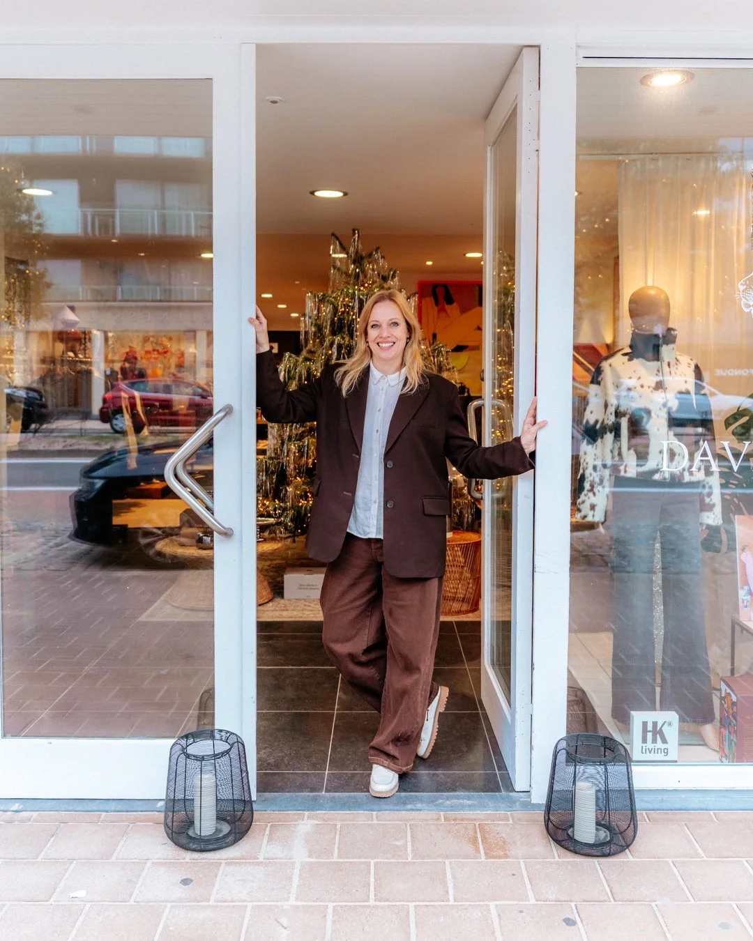 Marijke Verbrugghe zaakvoerder van David & Dupont kijkt lachend naar de camera in de toegang van haar concept store.