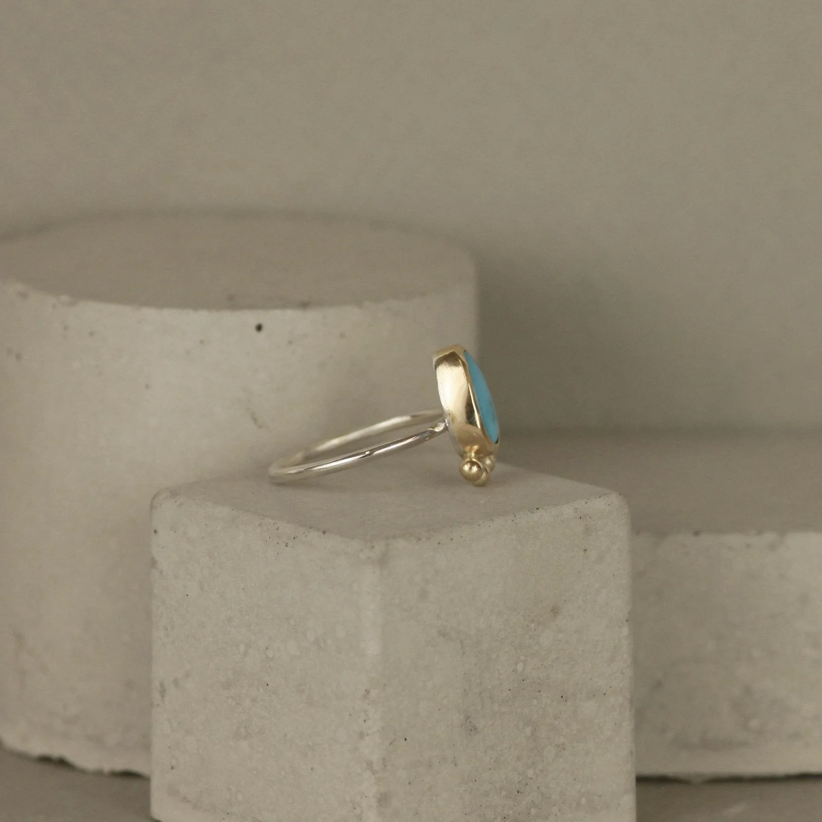 side view of Small blue gemstone pear shaped ring in gold setting