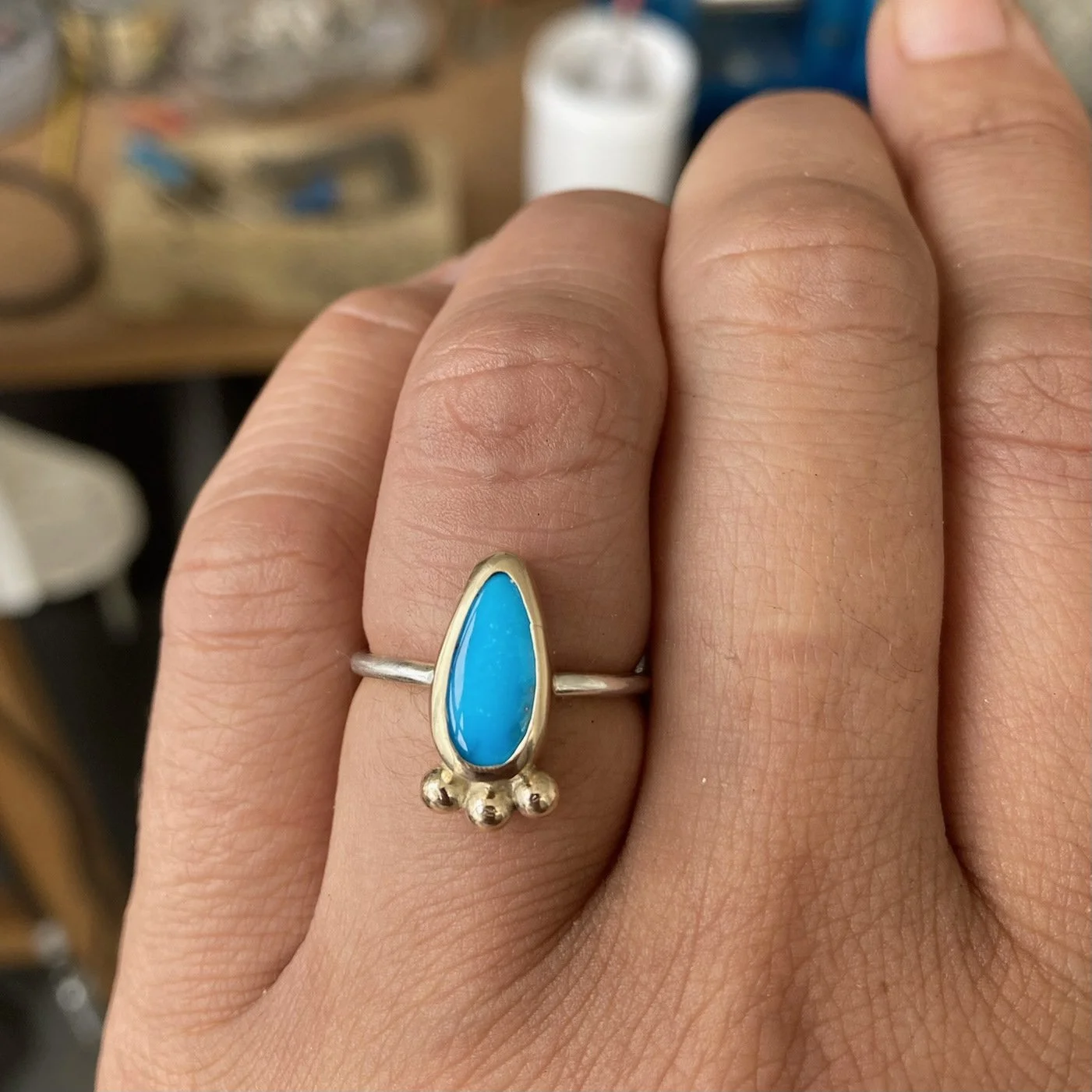 Small teardrop turquoise crystal gold and silver ring shown on a finger