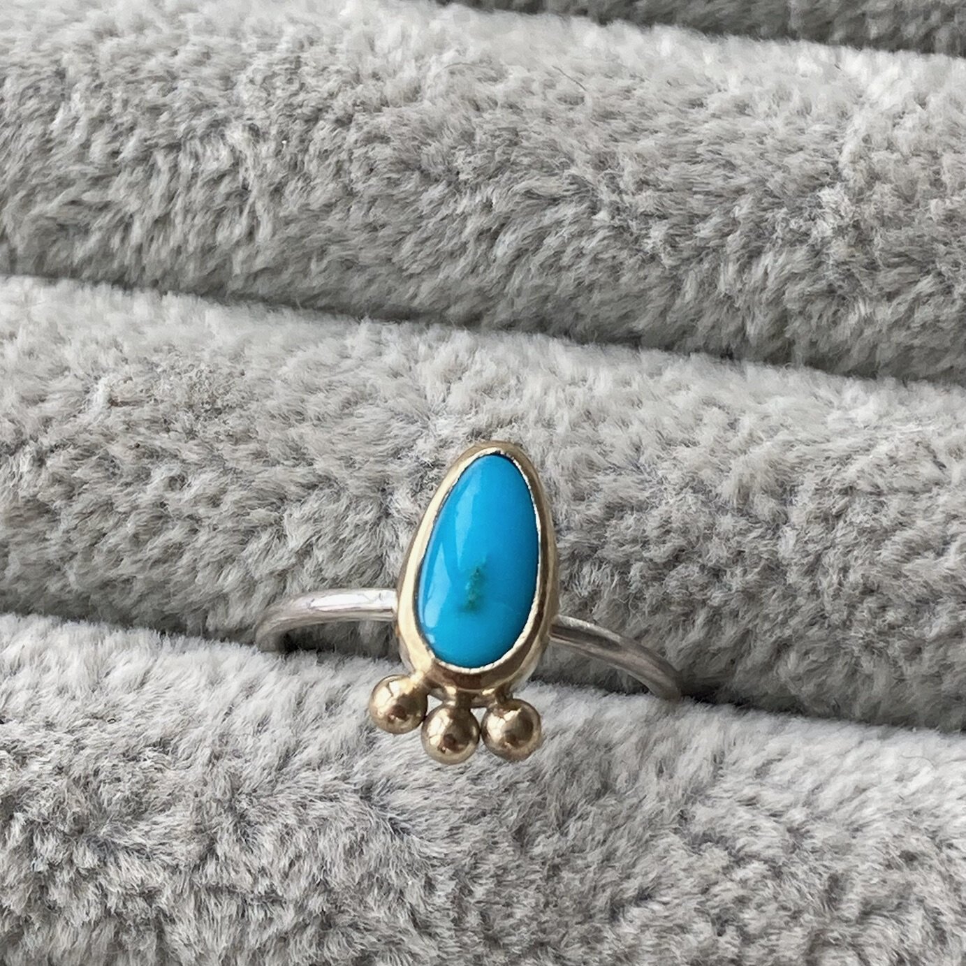 Small blue gemstone pear shaped ring in gold setting with three gold studs