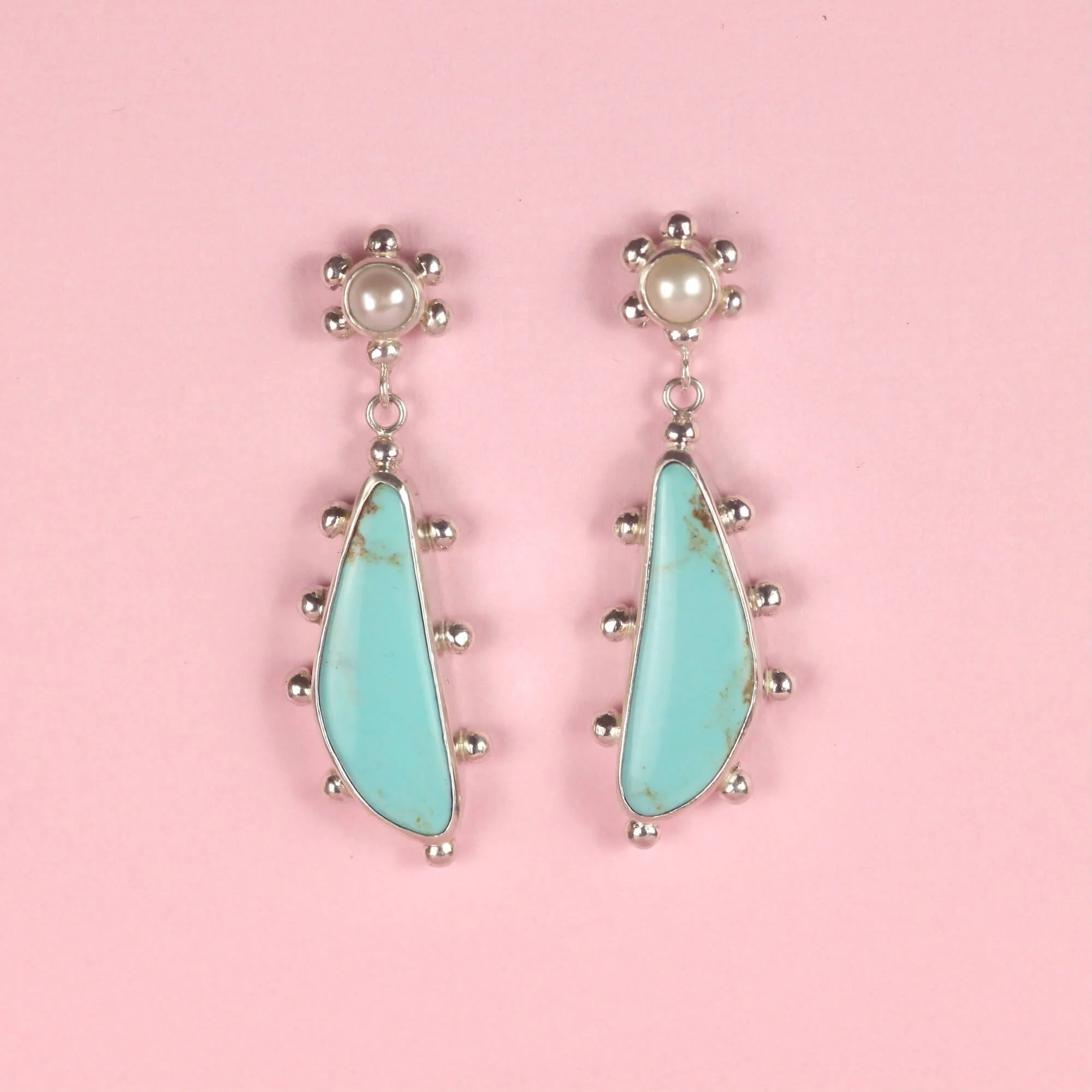 Long dangle earrings with stud backs with small round pearl cabochons and irregular shaped sky blue turquoise cabochons set in sterling silver bezels and decorated with silver studs