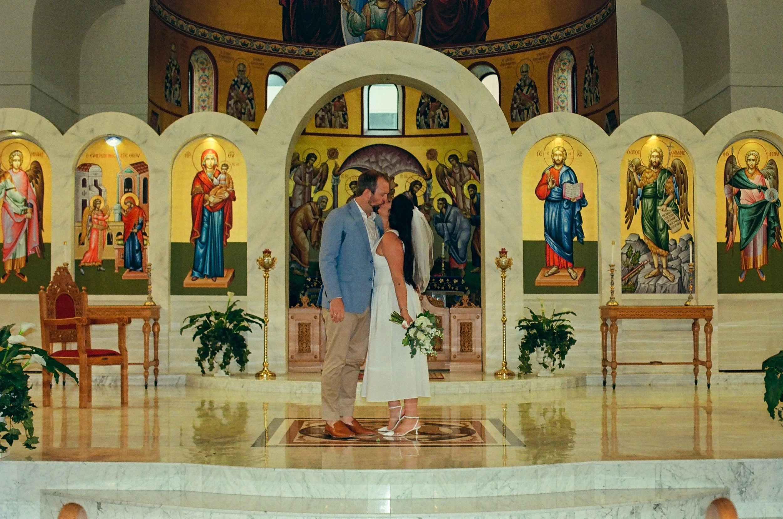 husband and wife in greek orthodox church in detroit kissing on the alter after wedding ceremony