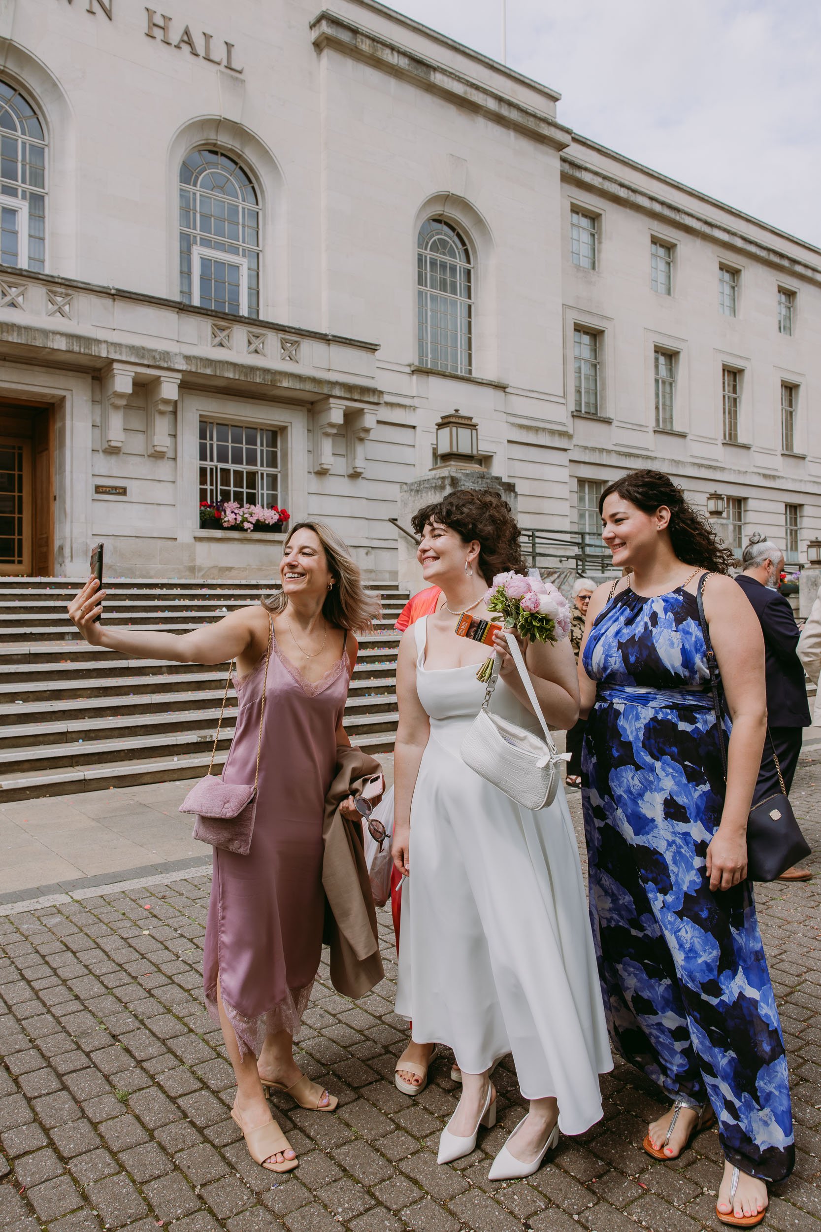 bride and friends taking photos after wedding at hackney town hall in London