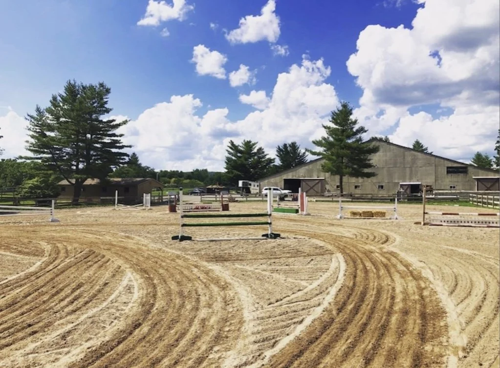 Freshly dragged outdoor arena with jump course set.