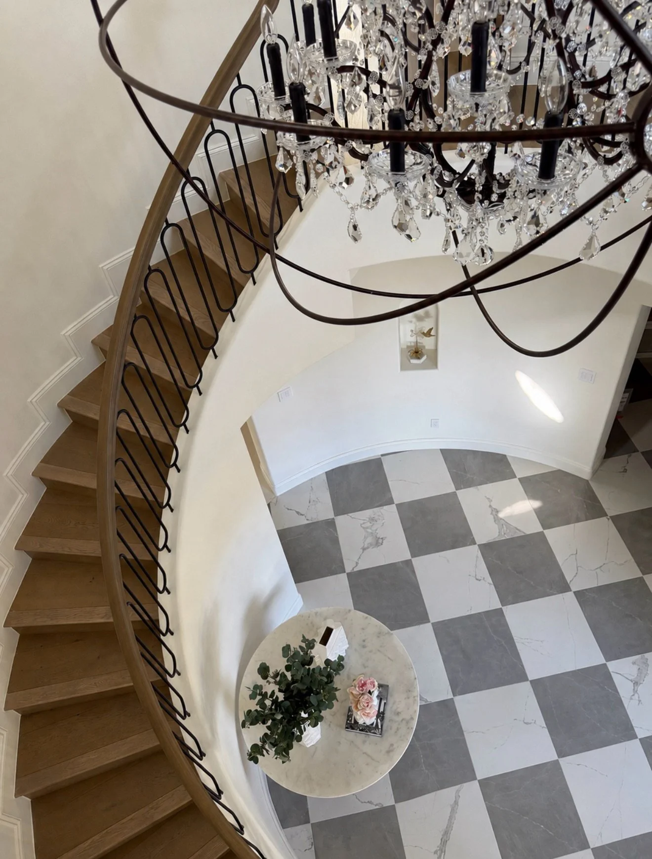 Still not the official project photos, but this view deserved a post.

A completely redesigned entry centered around the curved staircase, custom ironwork and checkerboard stone floor.

Traditional bones, cleaner detailing, strong contrast and a litt
