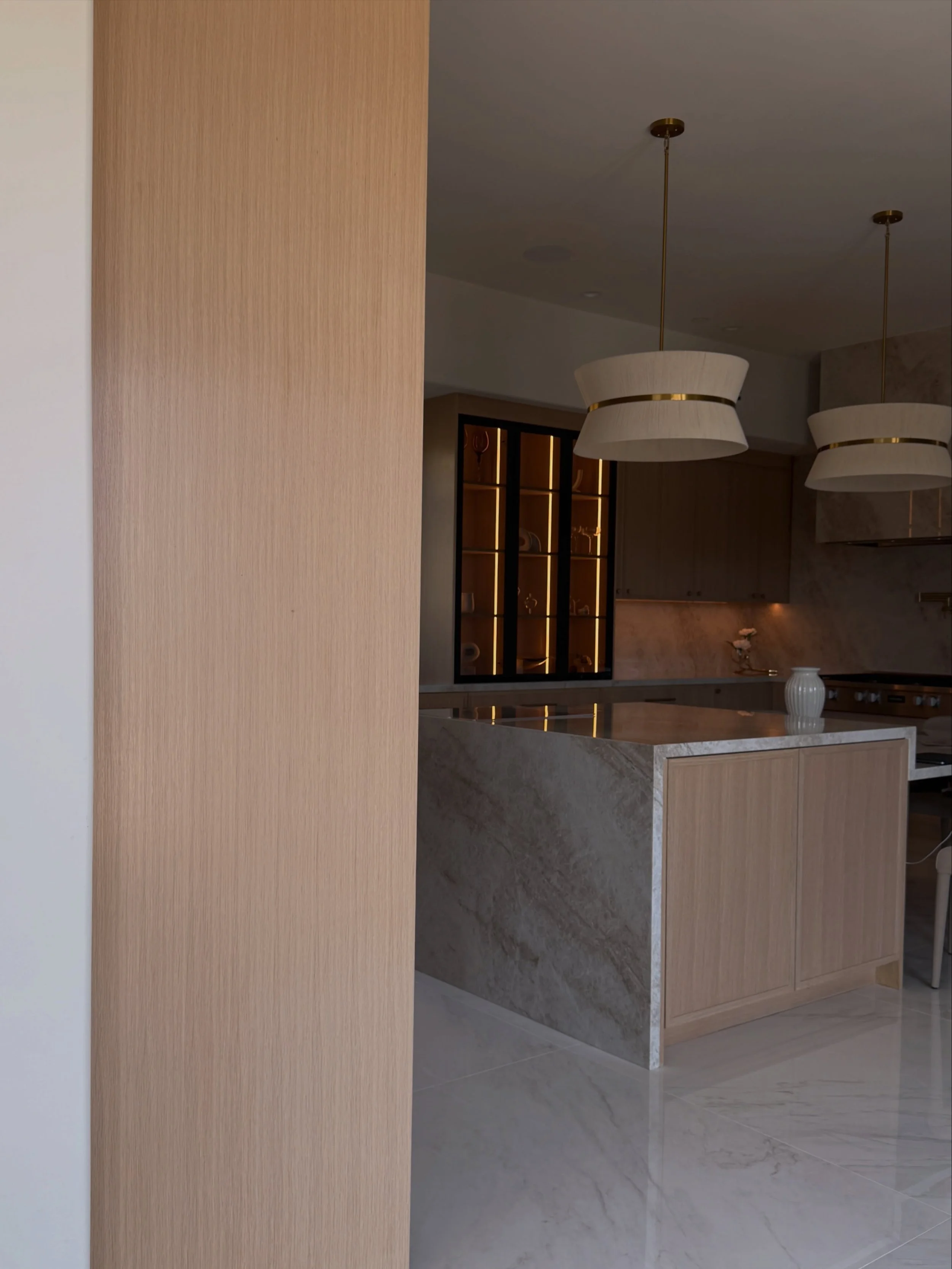 With this kitchen, I wanted all the function to almost disappear into the design.

Refrigeration, ovens, storage and pantry were folded into the millwork so the room could read as one continuous composition. The stone wrapped hood anchors the range w