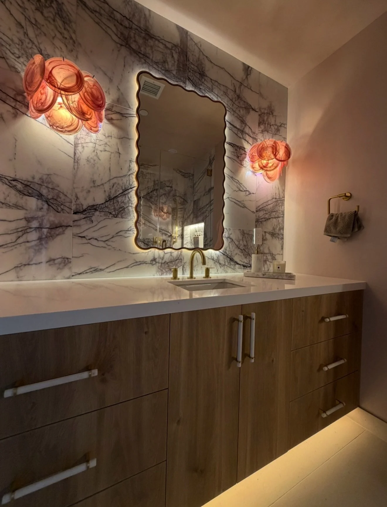 Designing for the youngest client in the house called for a little more play.
Her bedroom and bathroom carry the same softer language through both spaces, with custom built-ins, warm wood, blush tones, veined stone, brass and those little pink detail