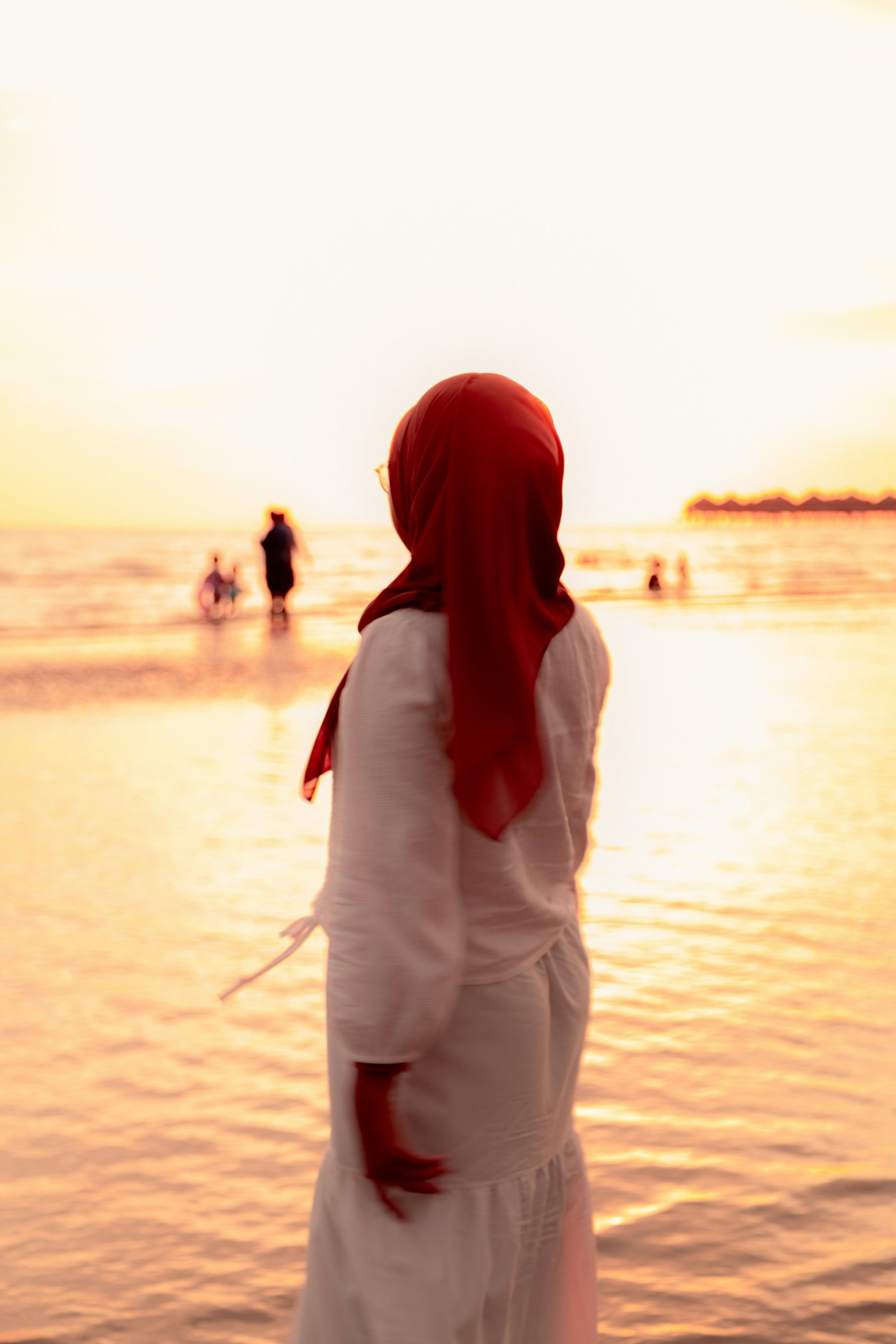 hijabi woman looking off into the distance on a calming beach