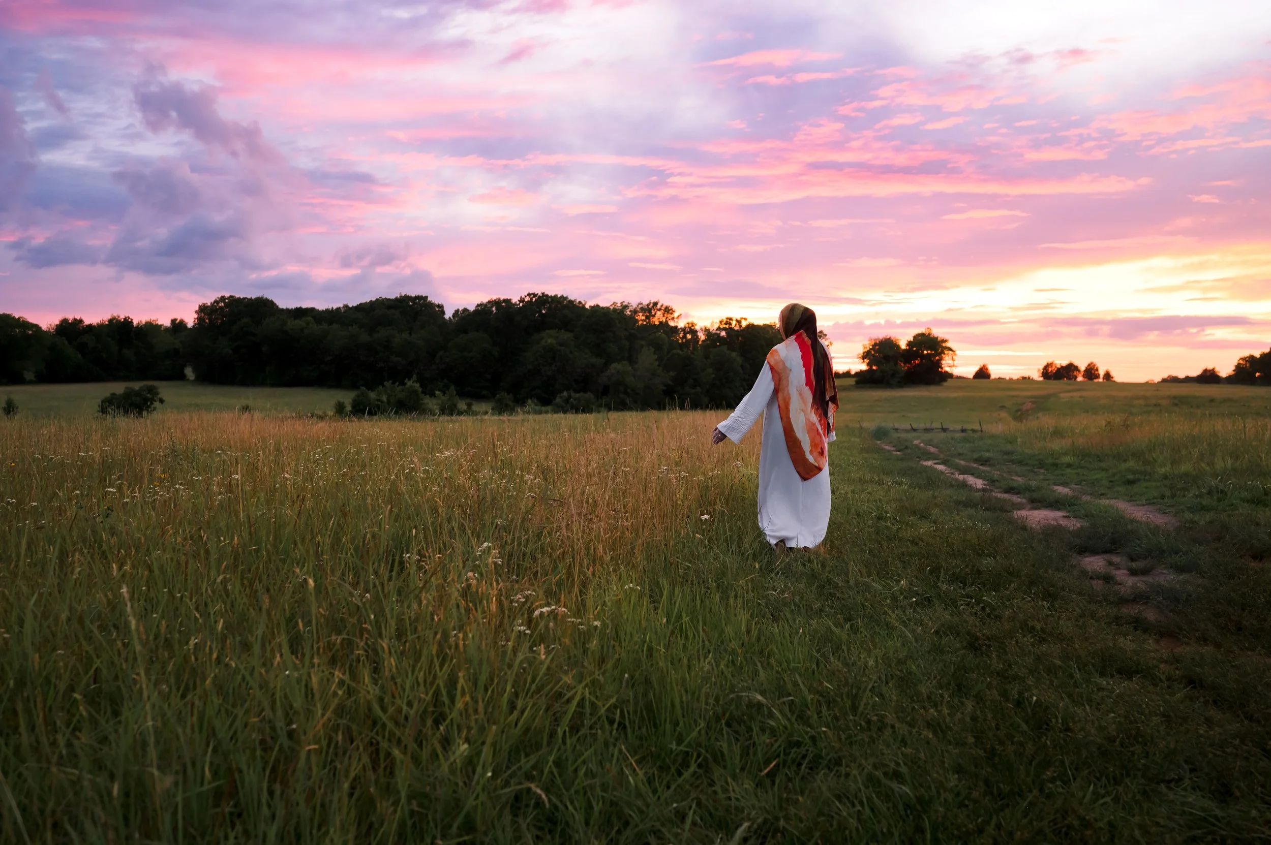Hijabi walking in a field towards the sunset feeling at peace.