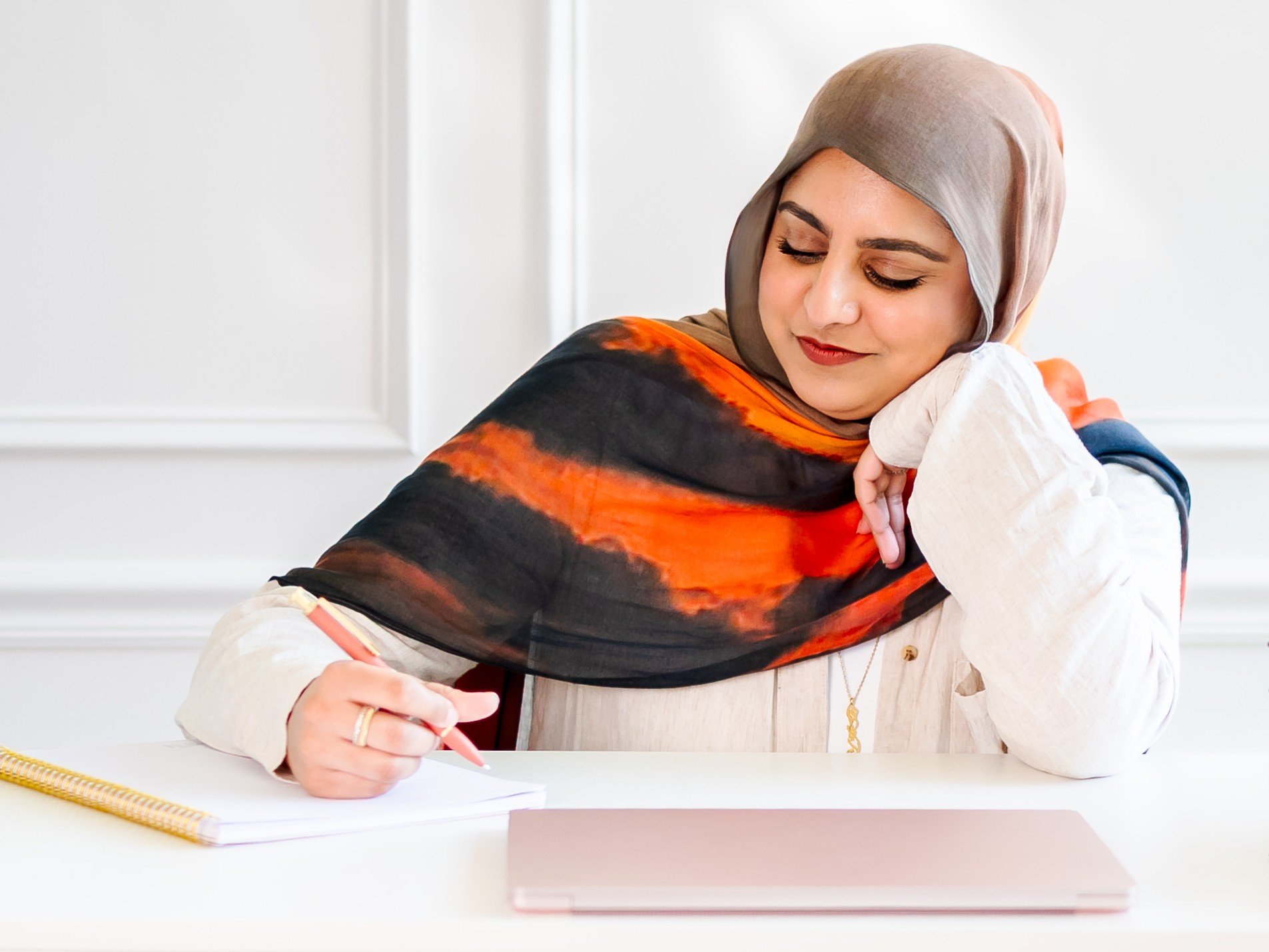 Natasha Deen, therapist, sitting at a desk taking notes with a pen and paper.