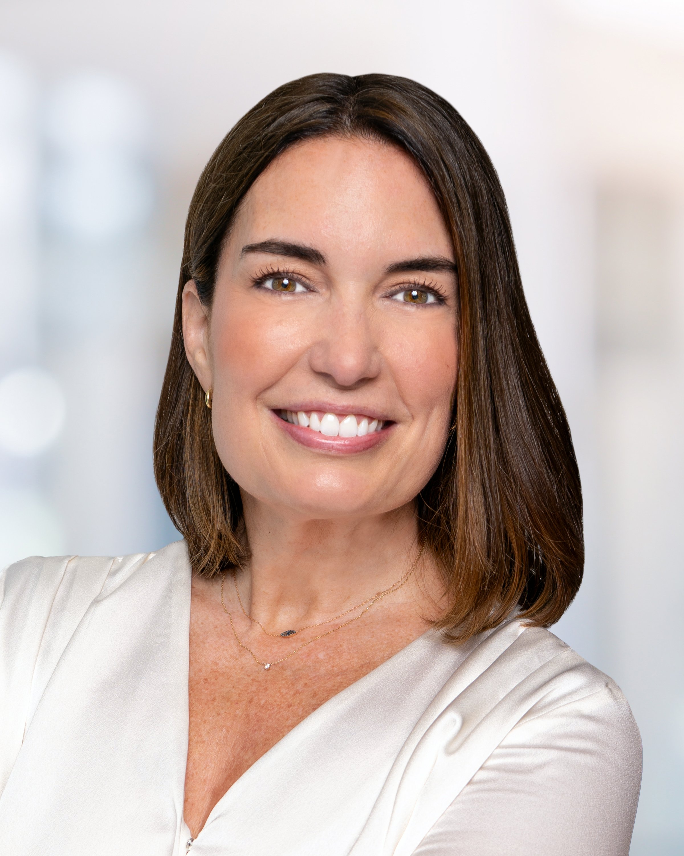 Professional headshot of Candace Dellacona, smiling and facing slightly to the side, with shoulder-length brown hair and a neutral background.