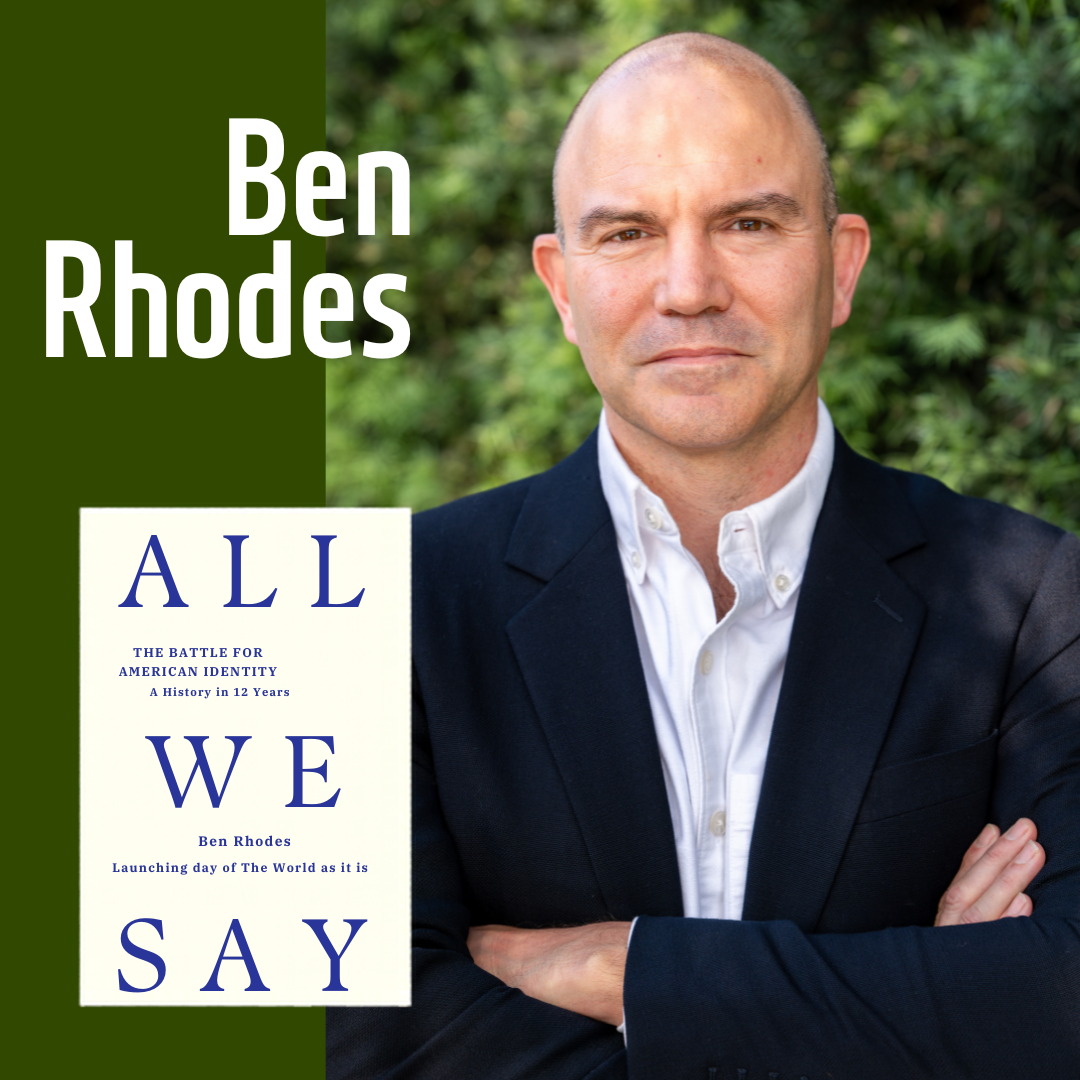 Ben Rhodes poses in a navy blue suit in front of greenery with his book "All We Say".