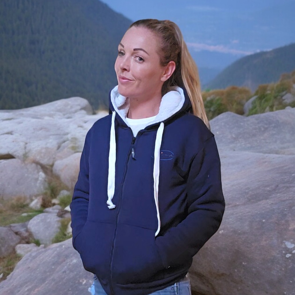 Louise McClintock stood on rocks wearing WaveMe StayDri short Blue hoody
