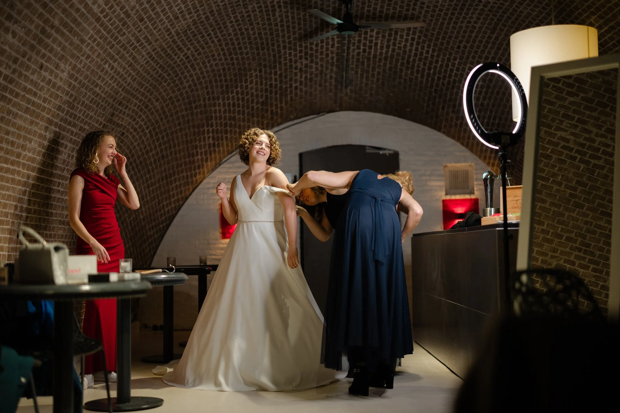 Getting ready van de bruid tijdens een winterbruiloft bij Fort Lent, aankleden van de trouwjurk in de gewelven