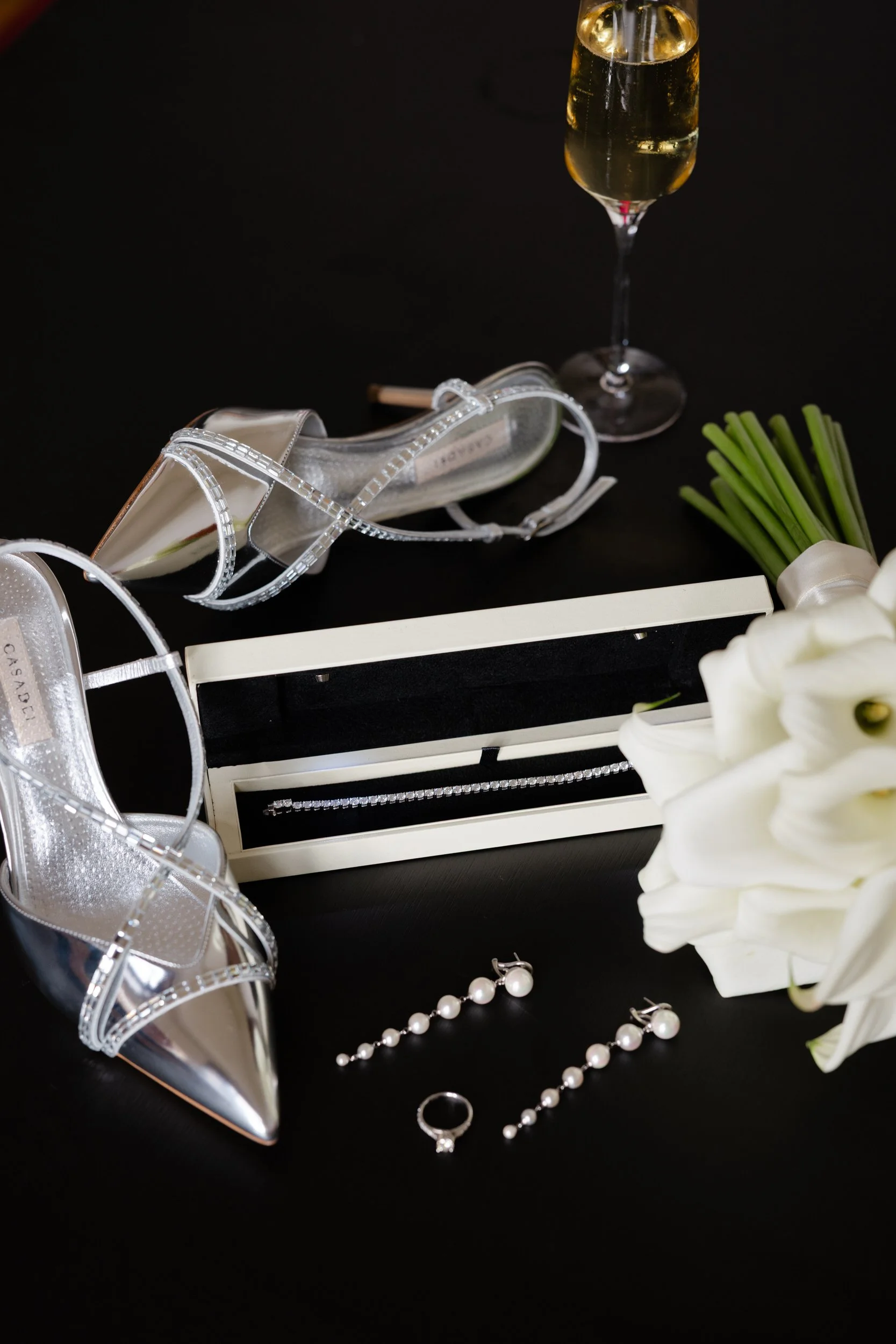   Detailfoto van accessoires van de bruid, schoenen, sieraden en bloemen tijdens de voorbereidingen bij Kasteel Delbrock in Maastricht  