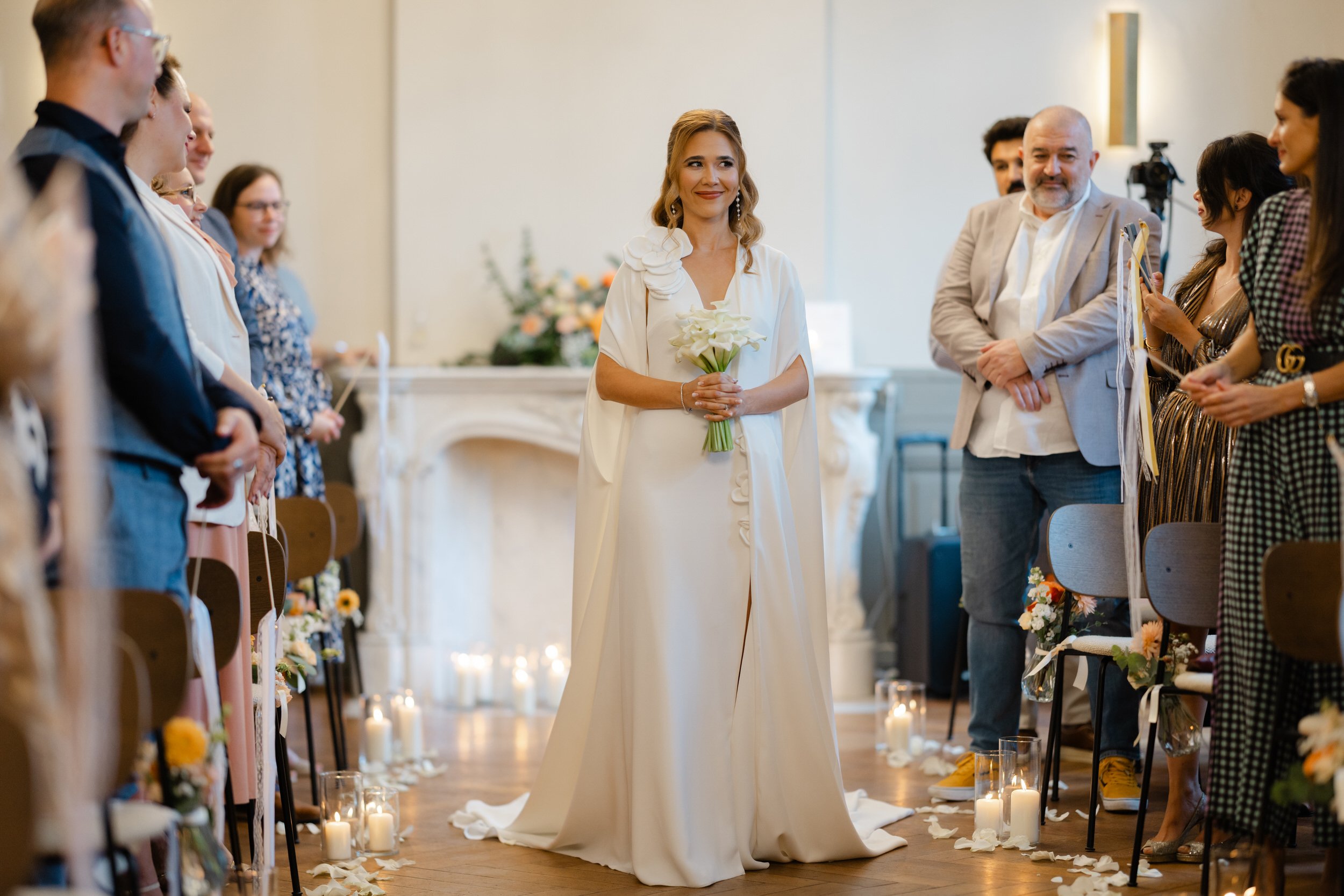   Bruid Irina tijdens de ceremonie, lopend door het gangpad omringd door gasten  