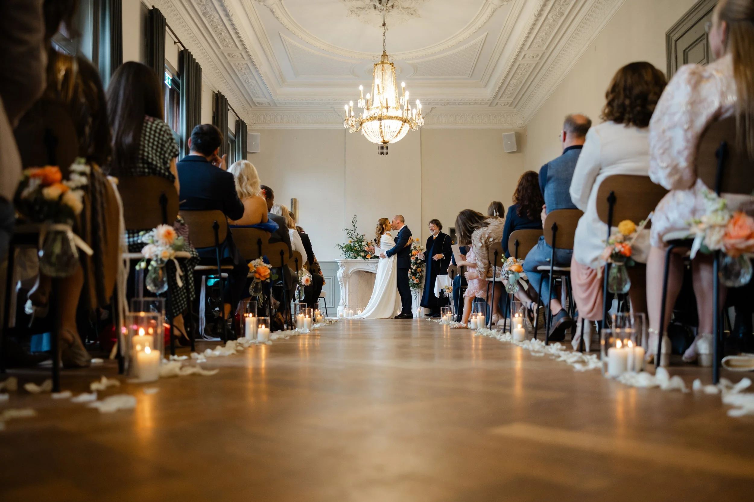   Overzicht van de ceremonie bij Kasteel Delbrock in Maastricht met het bruidspaar vooraan en gasten aan weerszijden  