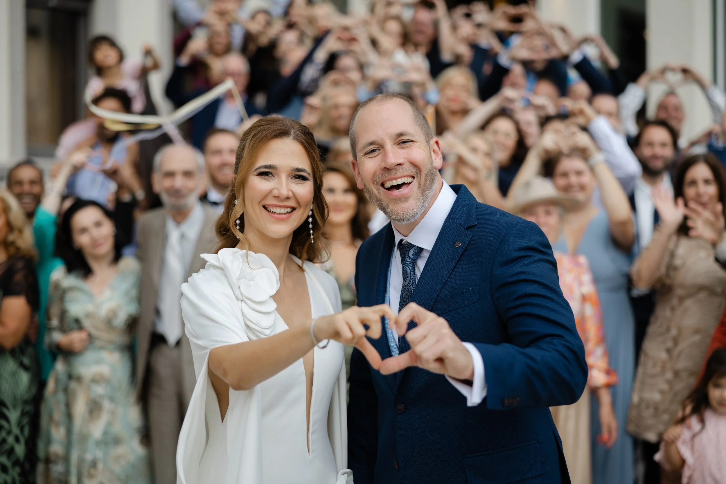   Bruidspaar lacht samen na de ceremonie bij Kasteel Delbrock, met gasten op de achtergrond  