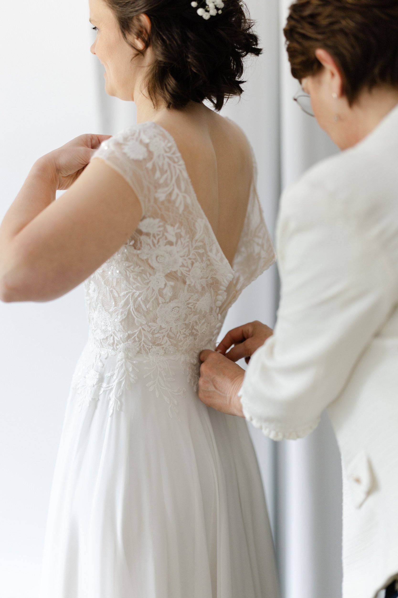   Monique wordt geholpen met het sluiten van haar trouwjurk tijdens de get ready bij Villa Klein Heumen  