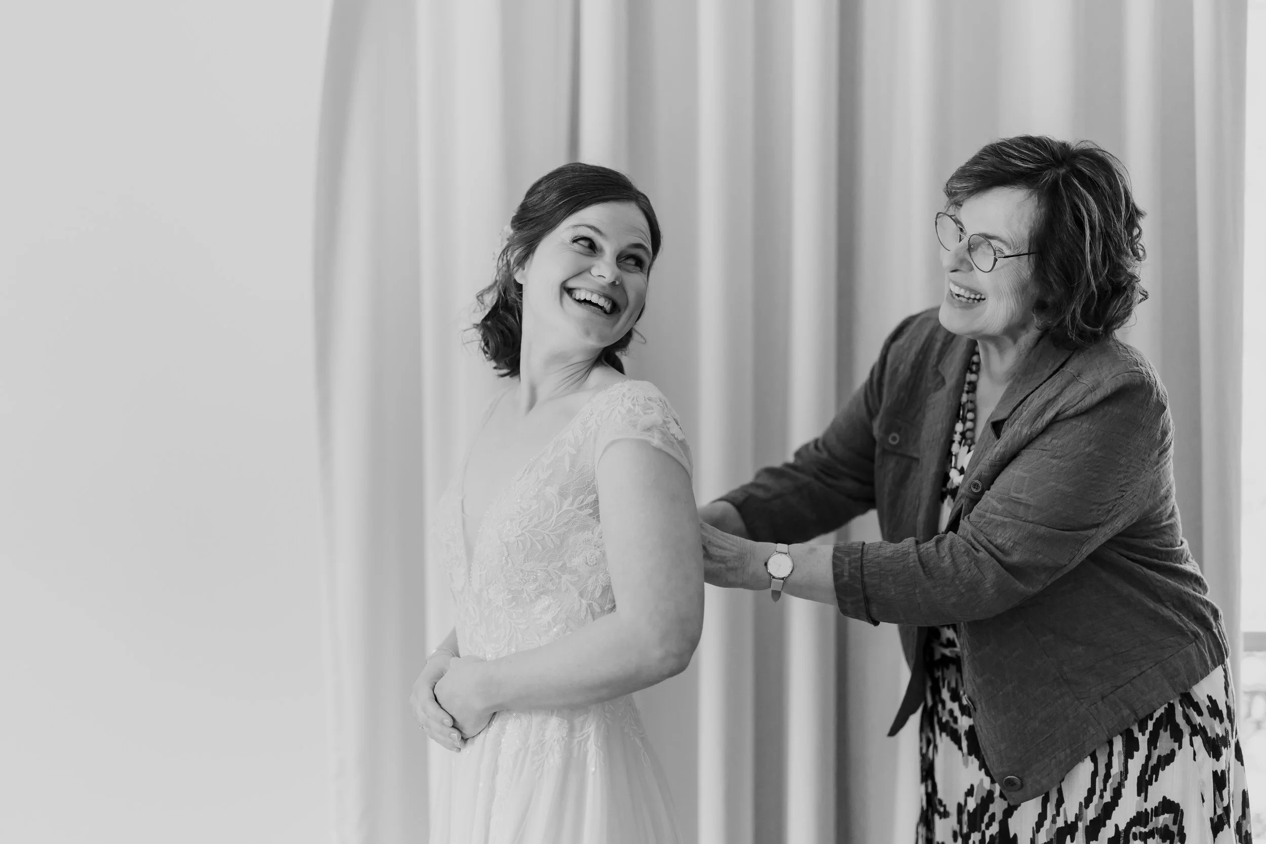   Monique lacht terwijl ze wordt geholpen met haar trouwjurk tijdens de get ready bij Villa Klein Heumen  