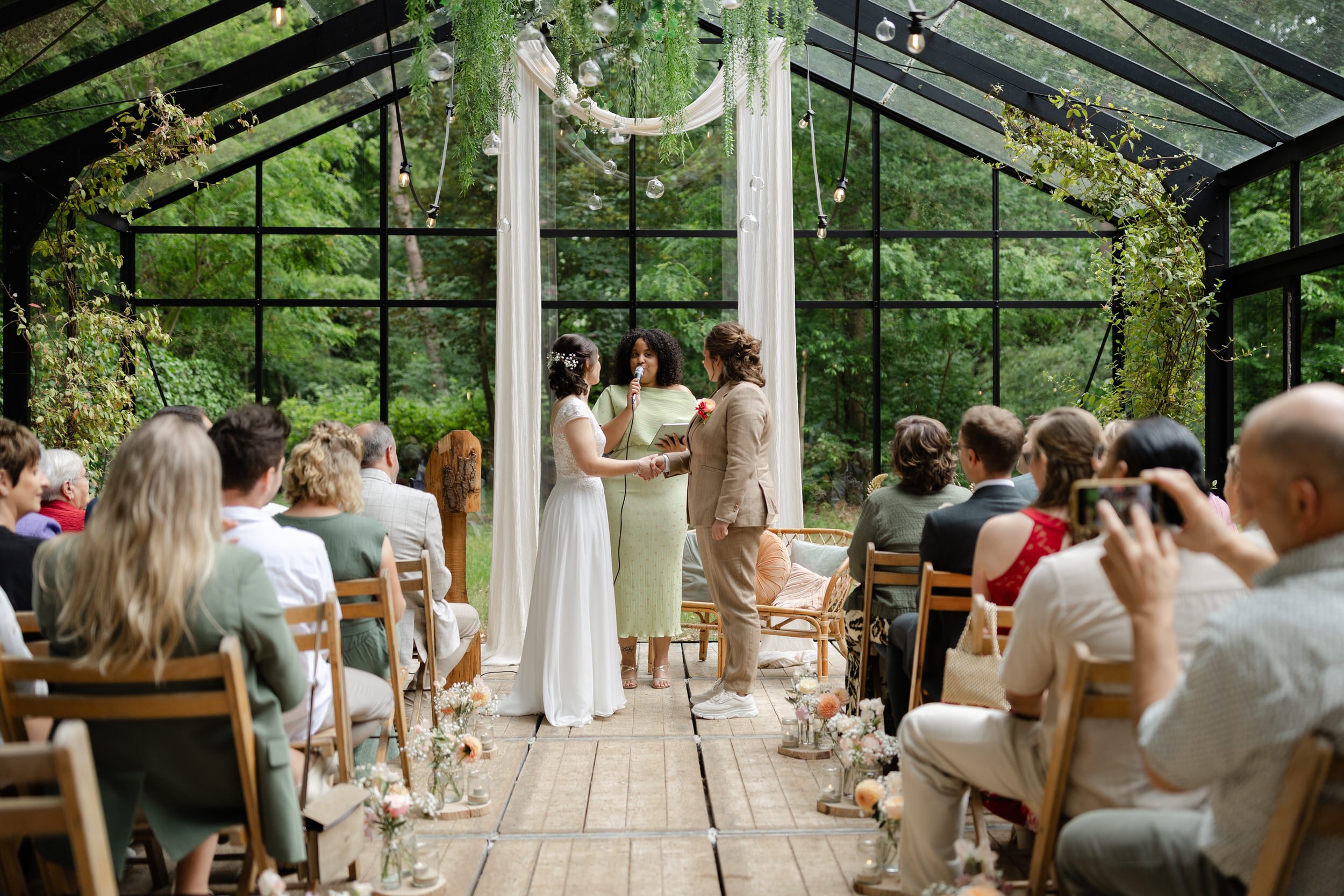   Evelien en Monique geven elkaar het jawoord tijdens hun ceremonie in de glazen boskas bij Villa Klein Heumen  